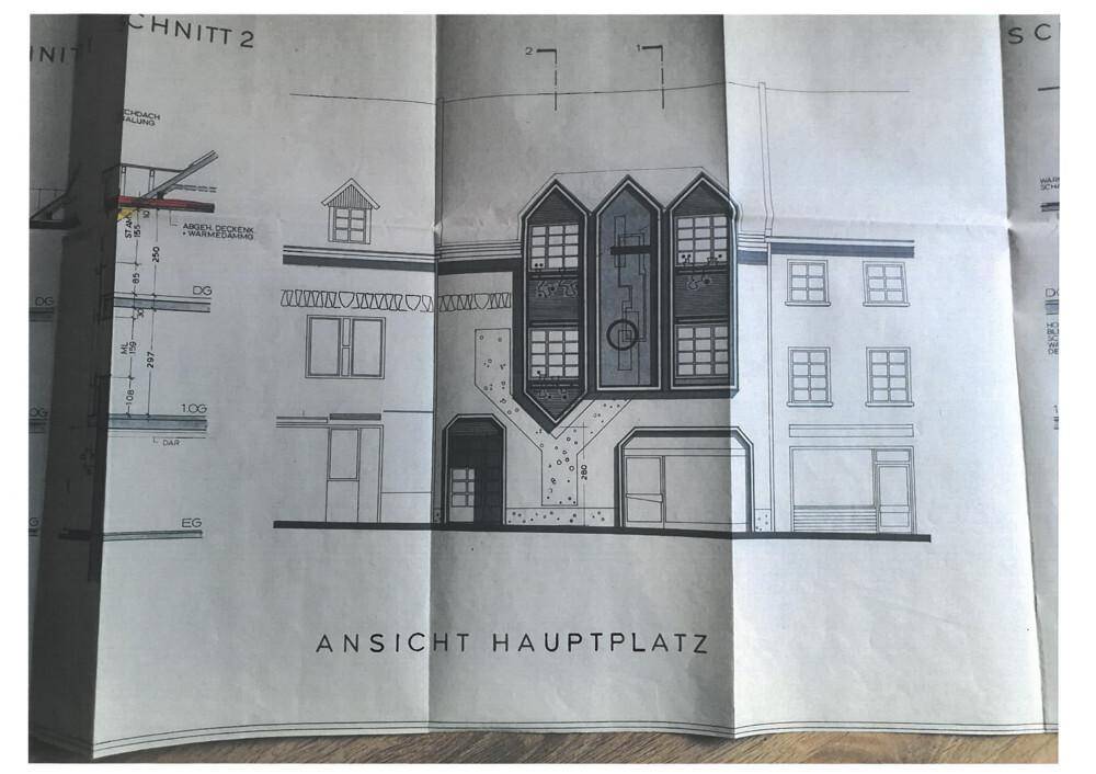 Architektonische Ansicht der Hauptfassade des Gebäudes mit Fenstern und Eingangsbereich.