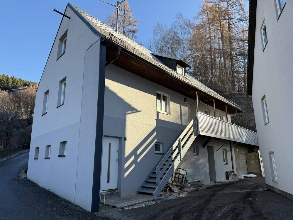 Außenansicht eines modernen Hauses an einem sonnigen Tag mit Treppe und Balkon.