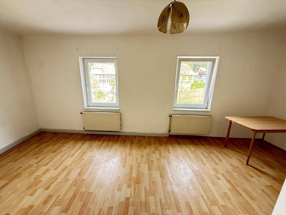 Helles Schlafzimmer im Dachgeschoss mit Laminatboden, zwei Fenstern und charakteristischen Dachschrägen.