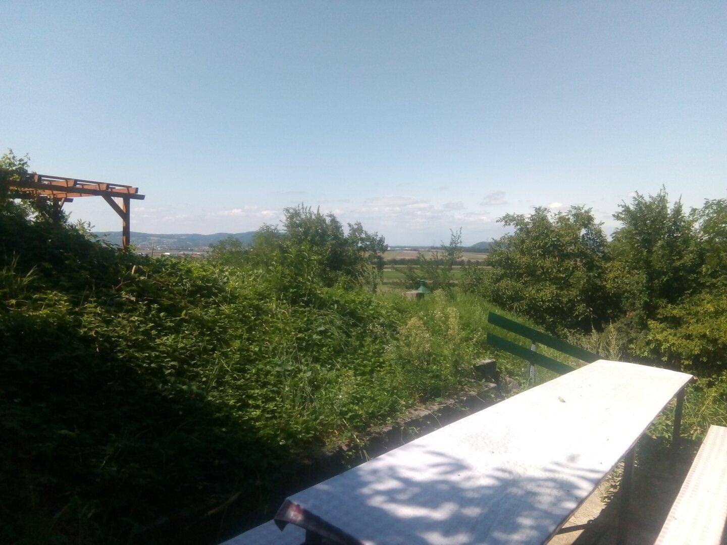 Sitzbereich im Freien mit Picknicktisch und weitem Blick über die grüne Landschaft.