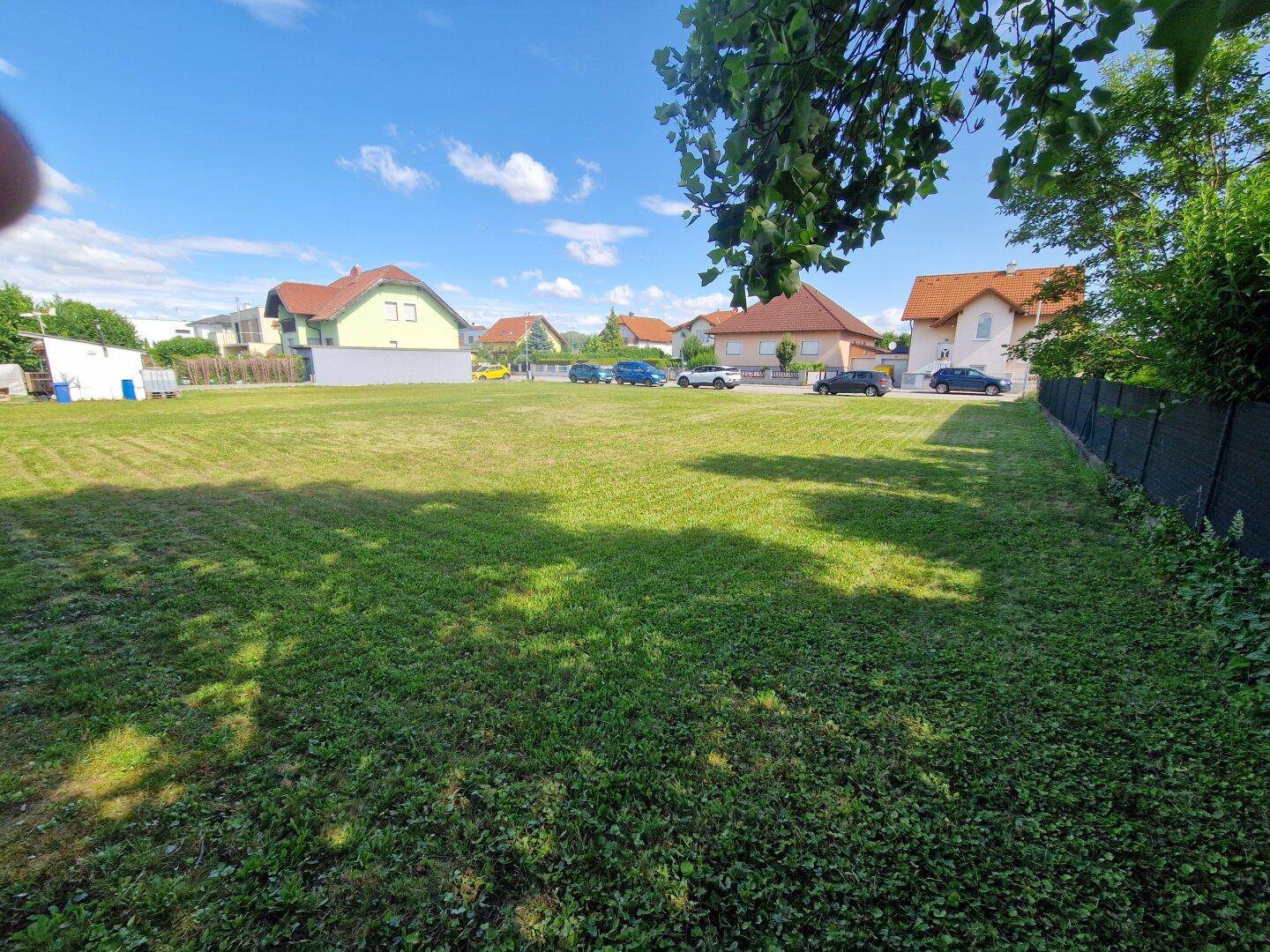 Offenes, sonniges Grundstück mit weitem Blick auf die umliegenden Wohnhäuser und den blauen Himmel.