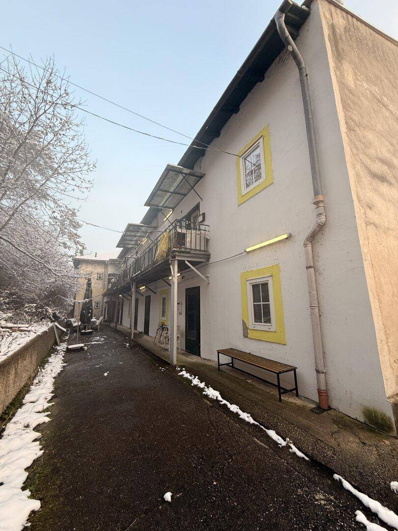Seitenansicht eines Gebäudes mit mehreren Balkonen und gelben Fensterrahmen im Winter.