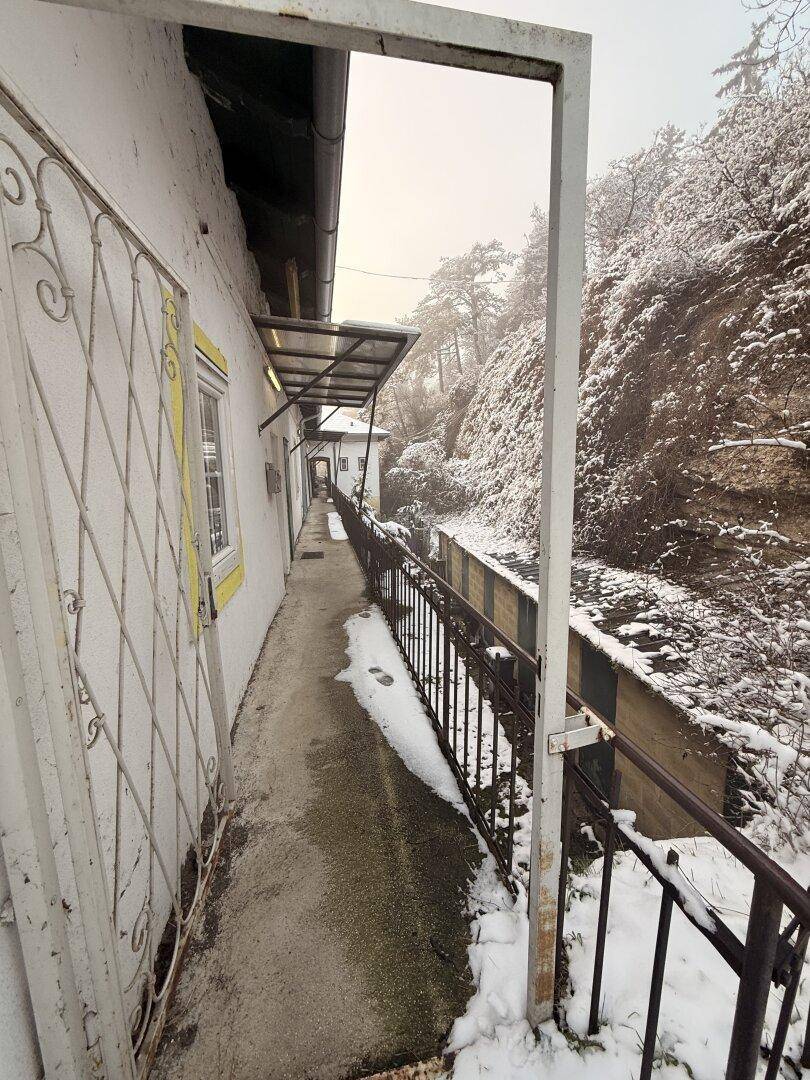 Langer, schmaler Gang entlang des Gebäudes mit Blick auf eine verschneite Böschung.