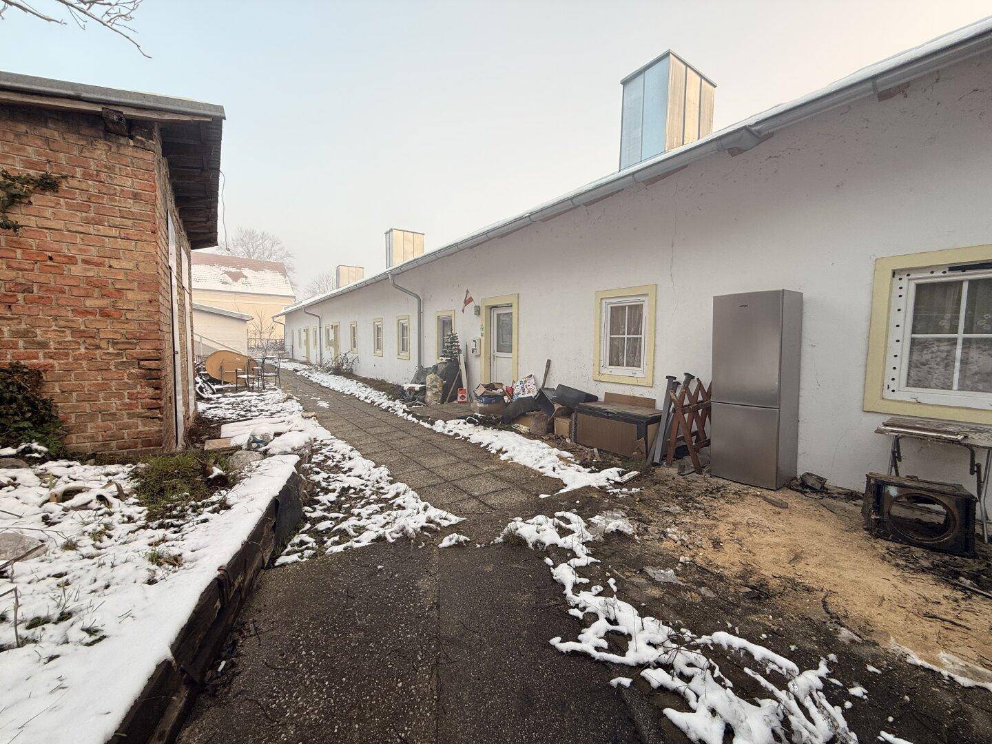 Seitenansicht eines Gebäudes mit gelben Fensterrahmen und einem Außenbereich mit Schnee.