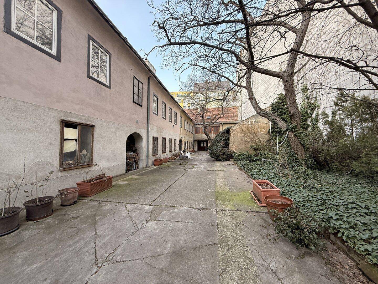 Gepflasterter Innenhof mit Bäumen und Gebäudefassaden, die eine ruhige Atmosphäre schaffen.