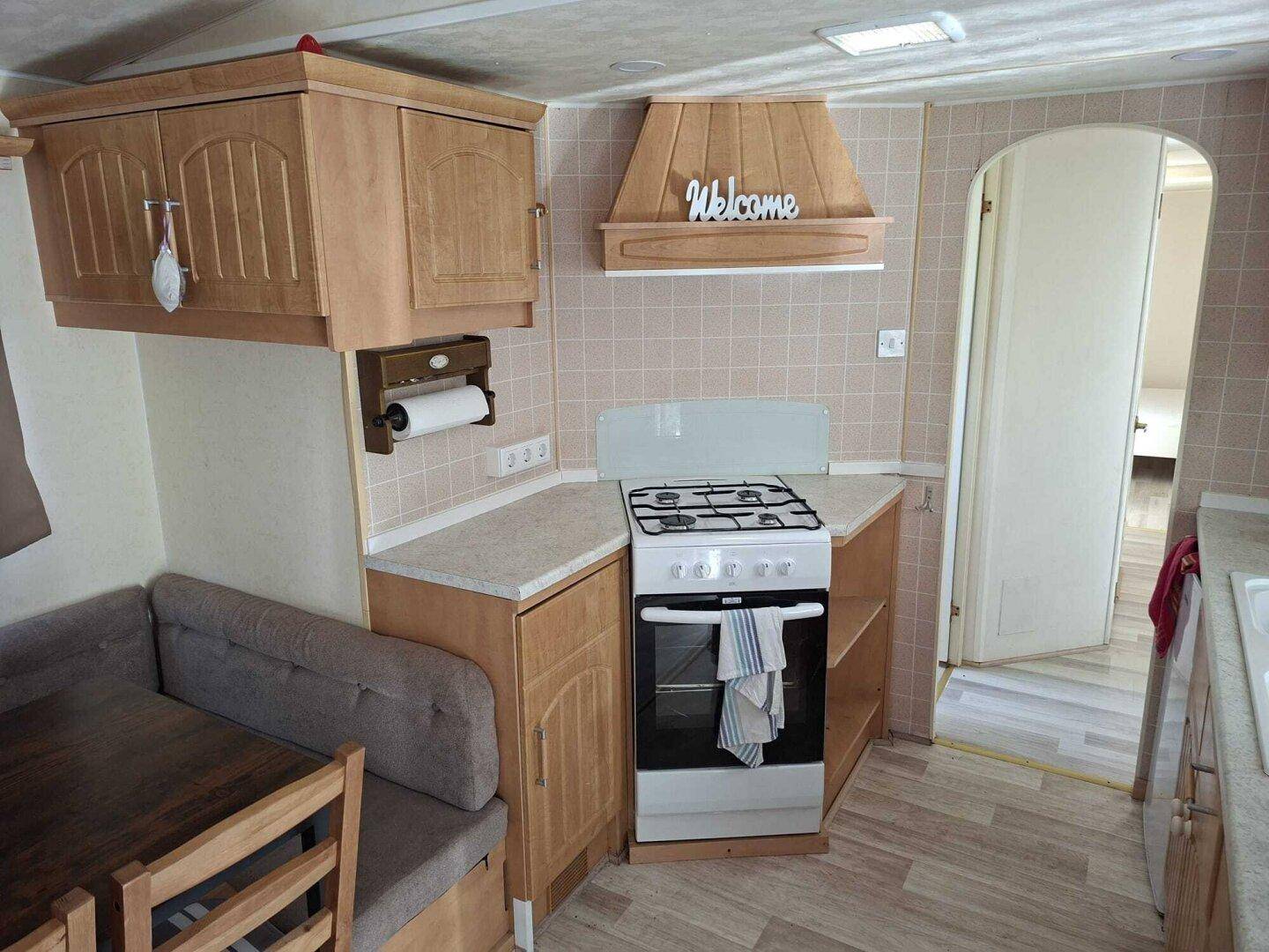 Funktionale Küche mit hellen Holzschränken, Gasherd und gefliestem Spritzschutz.