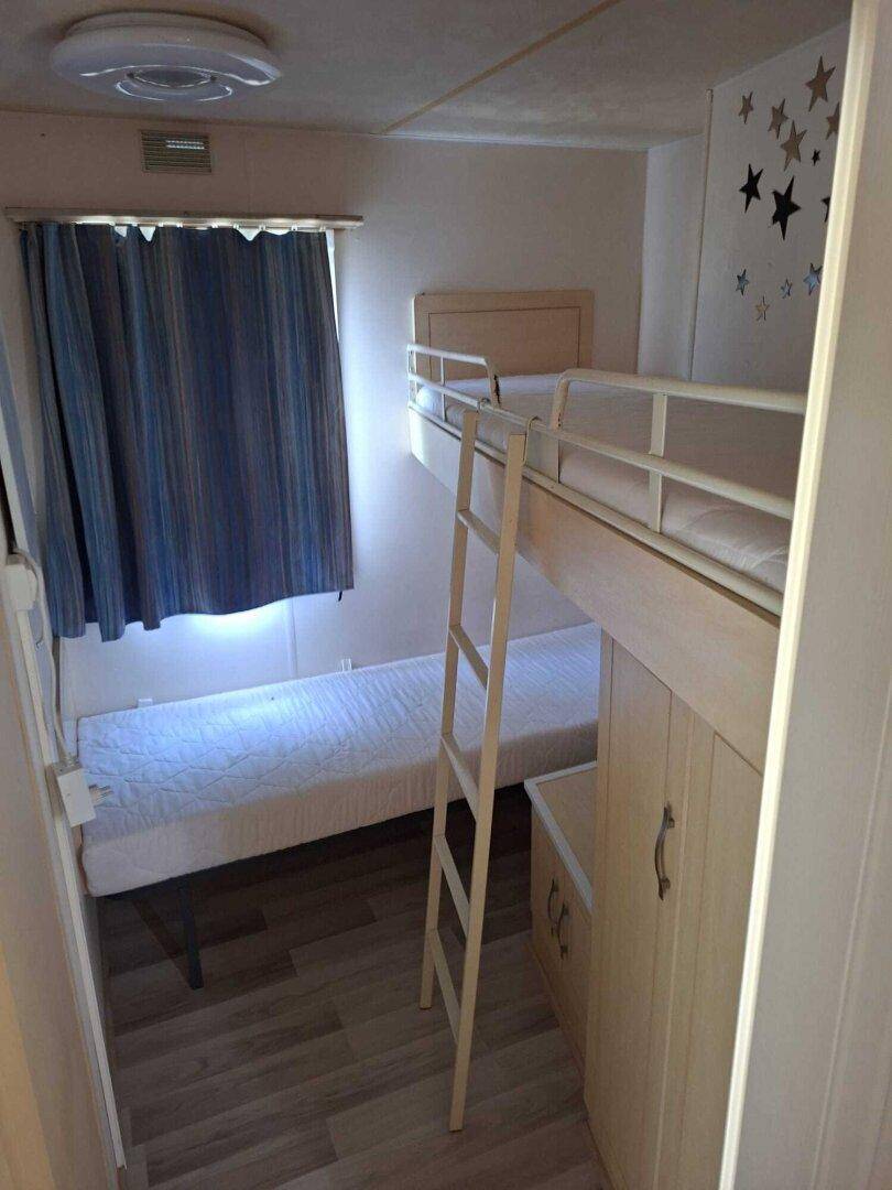 Kinderzimmer mit Etagenbett und kleinem Schrank.