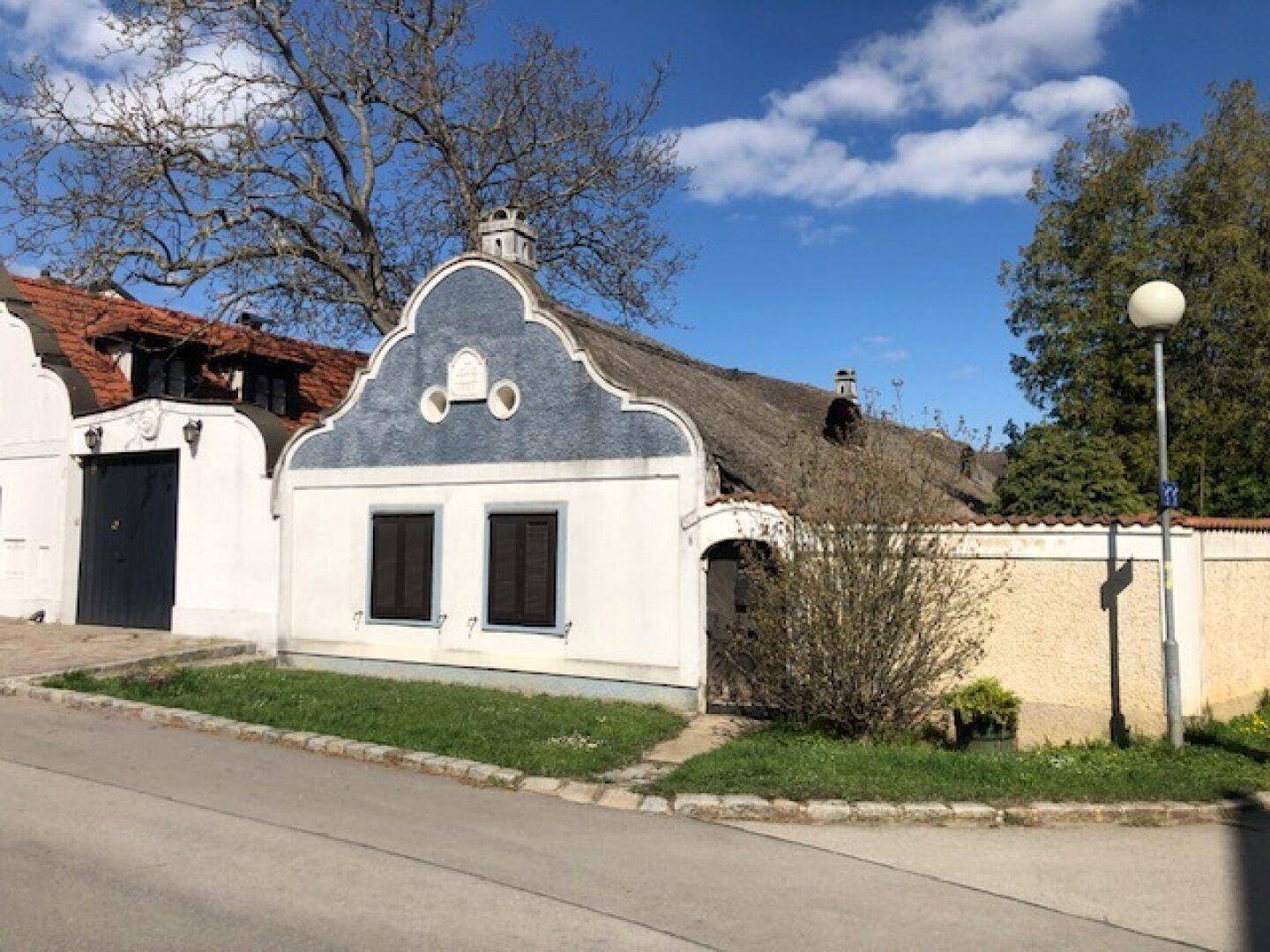 Charmantes traditionelles Haus mit einzigartiger Fassade und einem gut erhaltenen Reetdach unter strahlendem Sonnenschein.