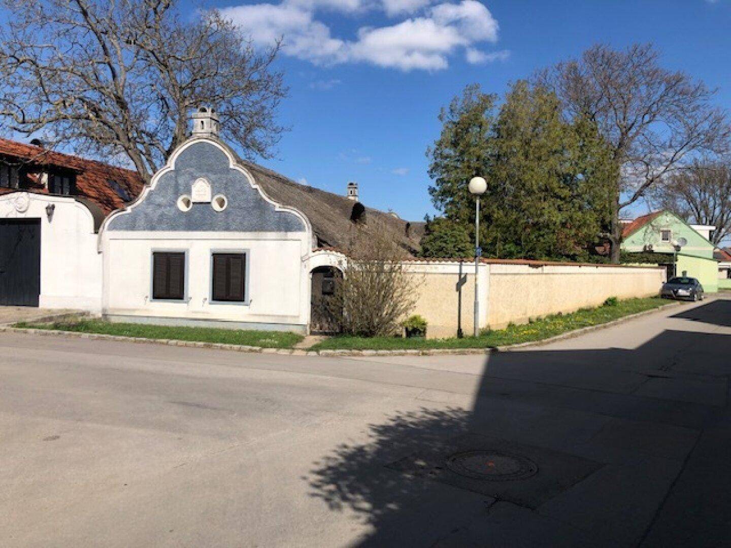Historisches Haus mit charakteristischer Fassade und Reetdach, eingebettet in eine ländliche Umgebung an einem sonnigen Tag.