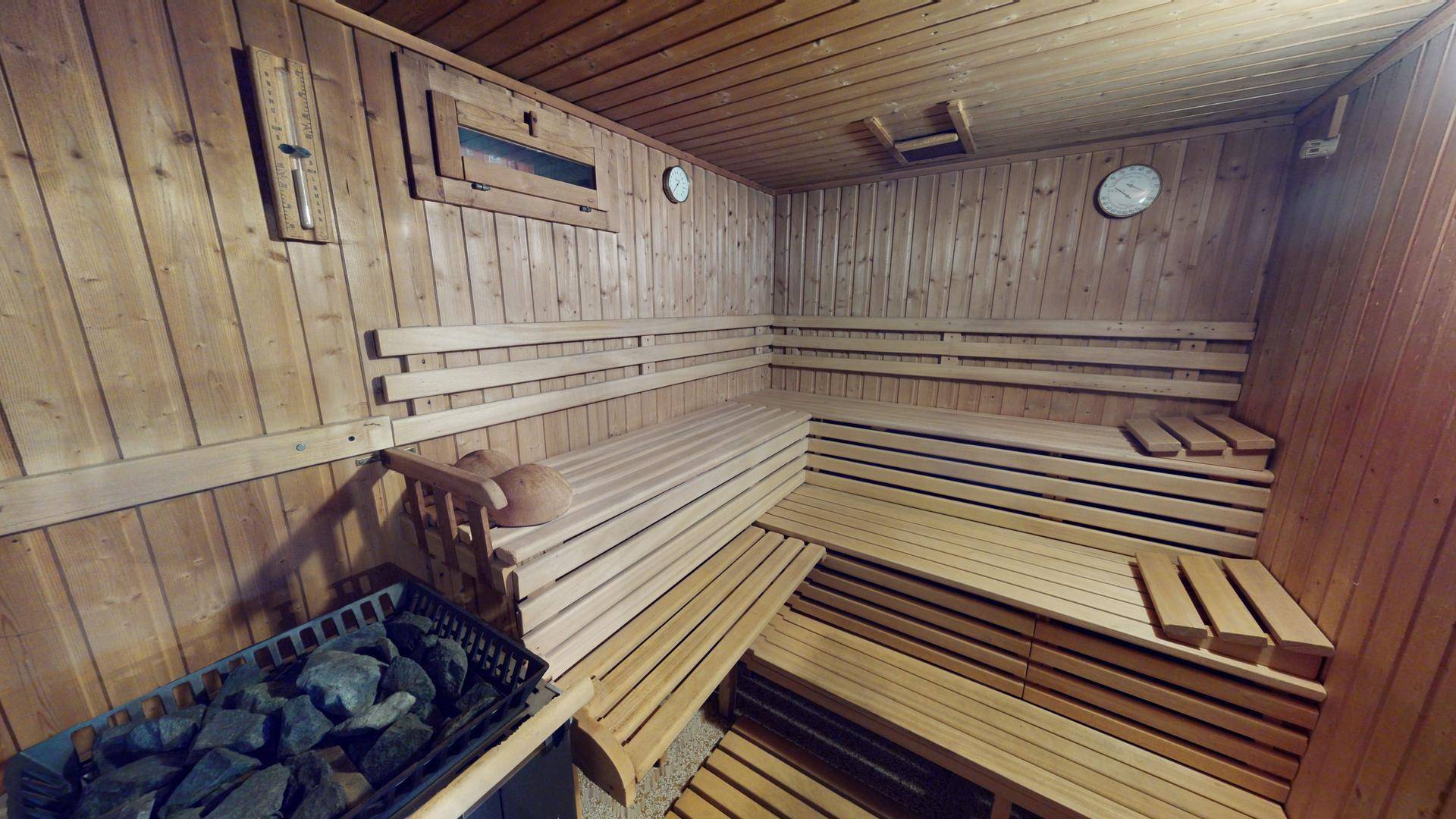 Traditionelle Holzsauna mit mehrstufigen Bänken und einem Saunaofen, bereit zur Entspannung.