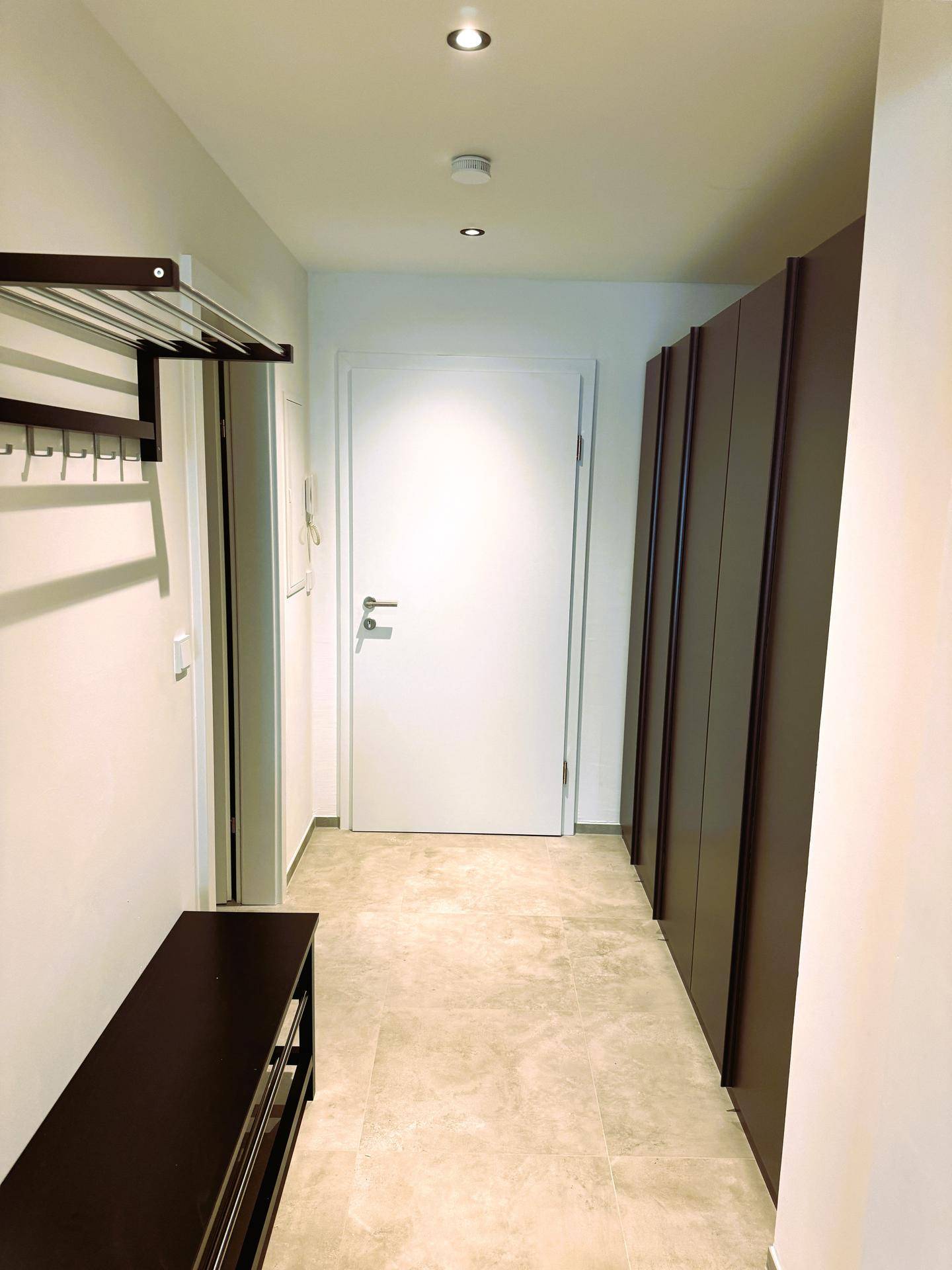 Heller Flur mit praktischen Einbauschränken, einer Garderobe und modernen Einbauleuchten an der Decke.
