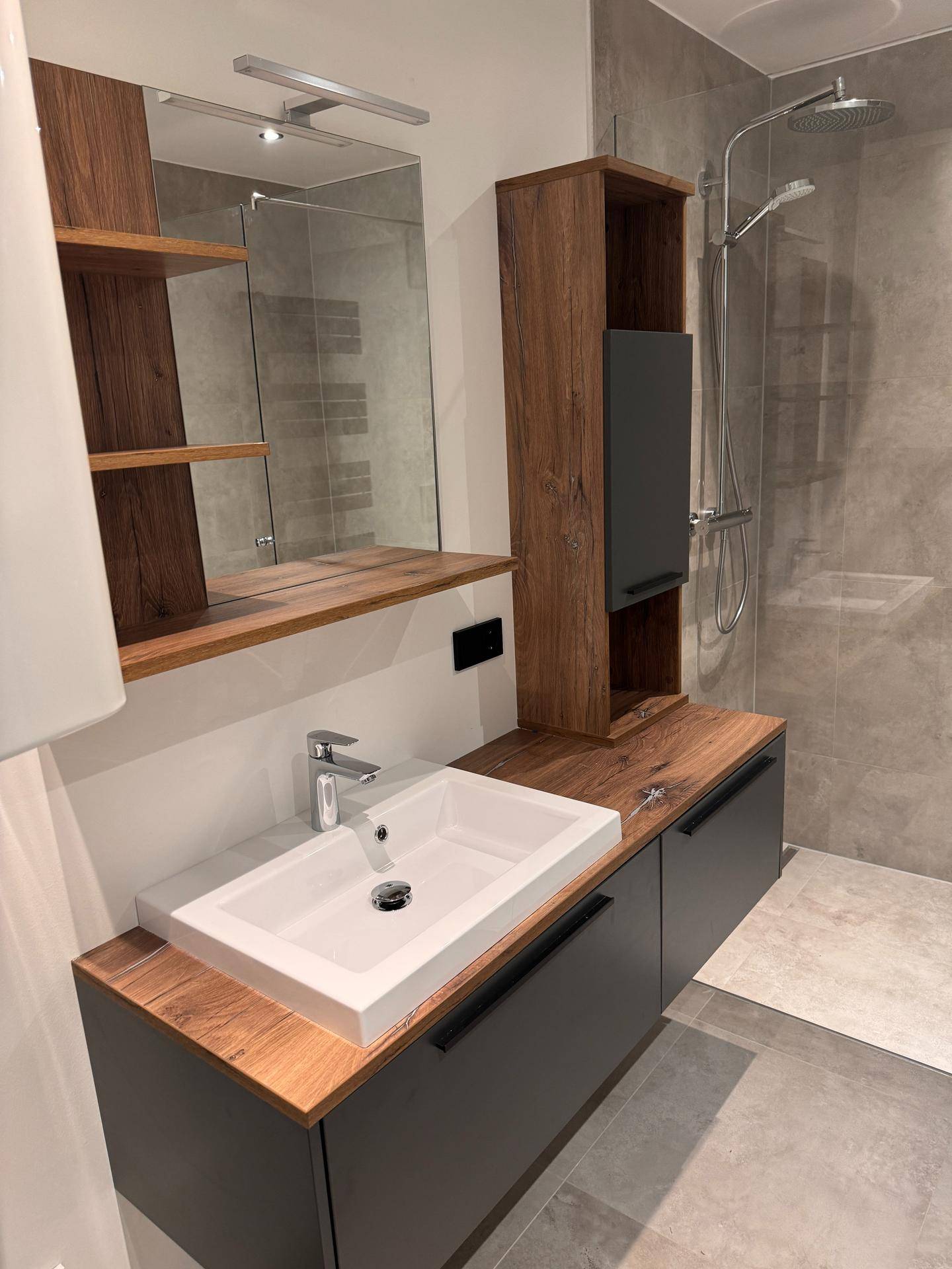 Modernes Badezimmer mit Holzakzenten, großformatigen Fliesen und einer geräumigen begehbaren Dusche.