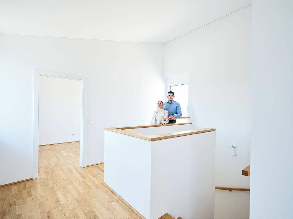 Heller Flurbereich mit Holztreppe und Parkettboden in einem modernen Neubau.