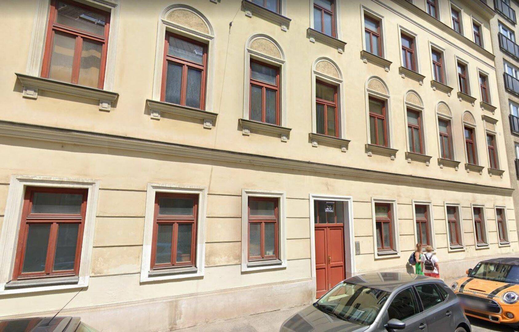 Historische Gebäudefassade mit vielen Fenstern und einer roten Eingangstür, typisch für die Stadtarchitektur.