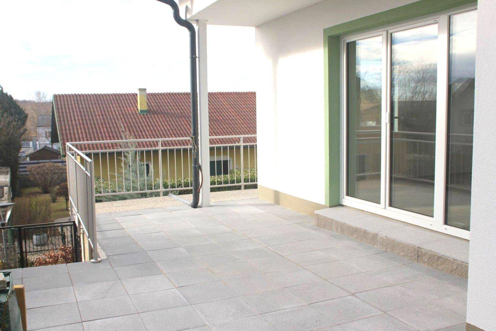 Geräumige, geflieste Terrasse mit Metallgeländer und Schiebetüren, ideal für Entspannung im Freien.