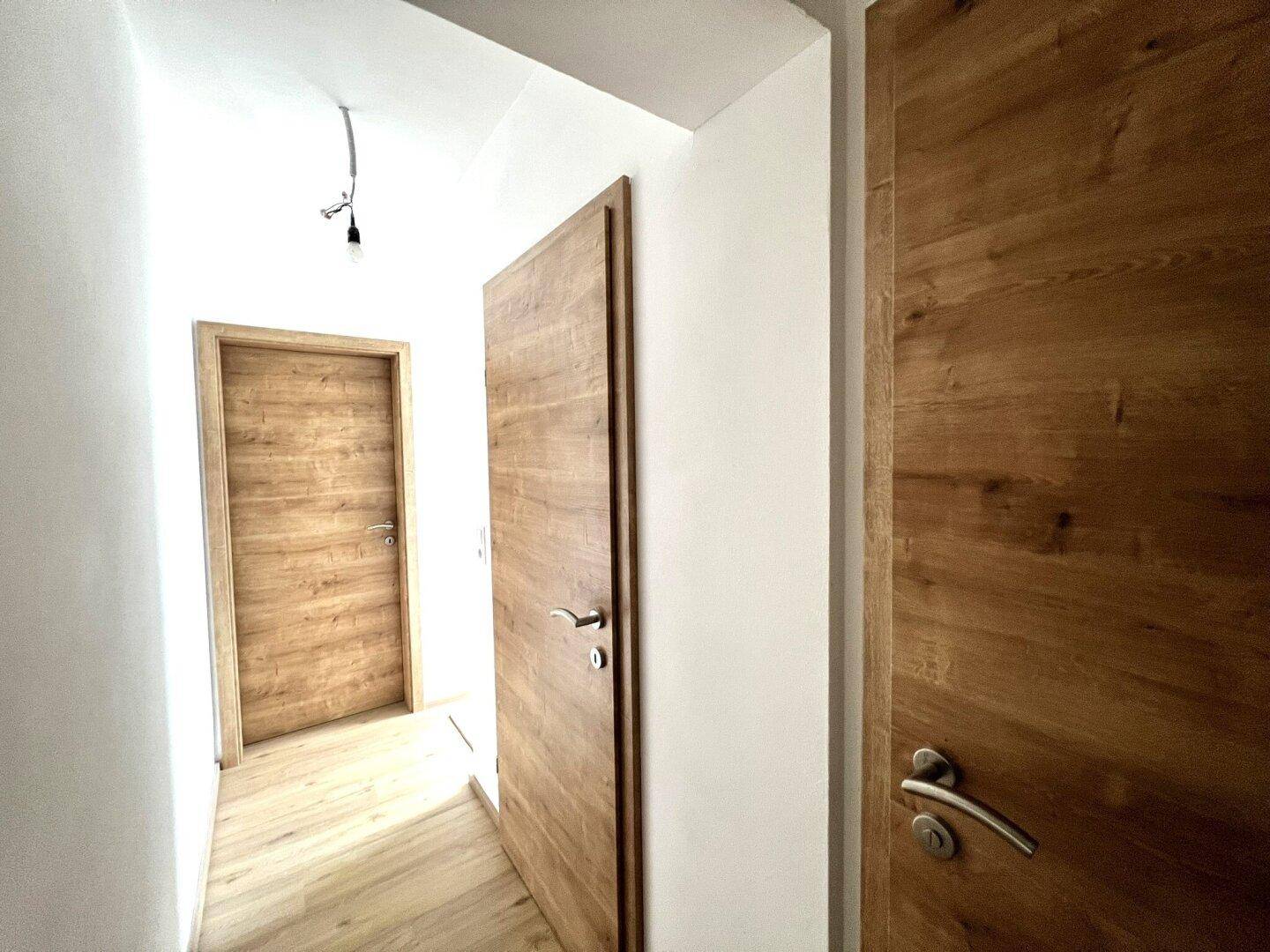 Heller Flur mit Laminatboden und mehreren modernen Holztüren.