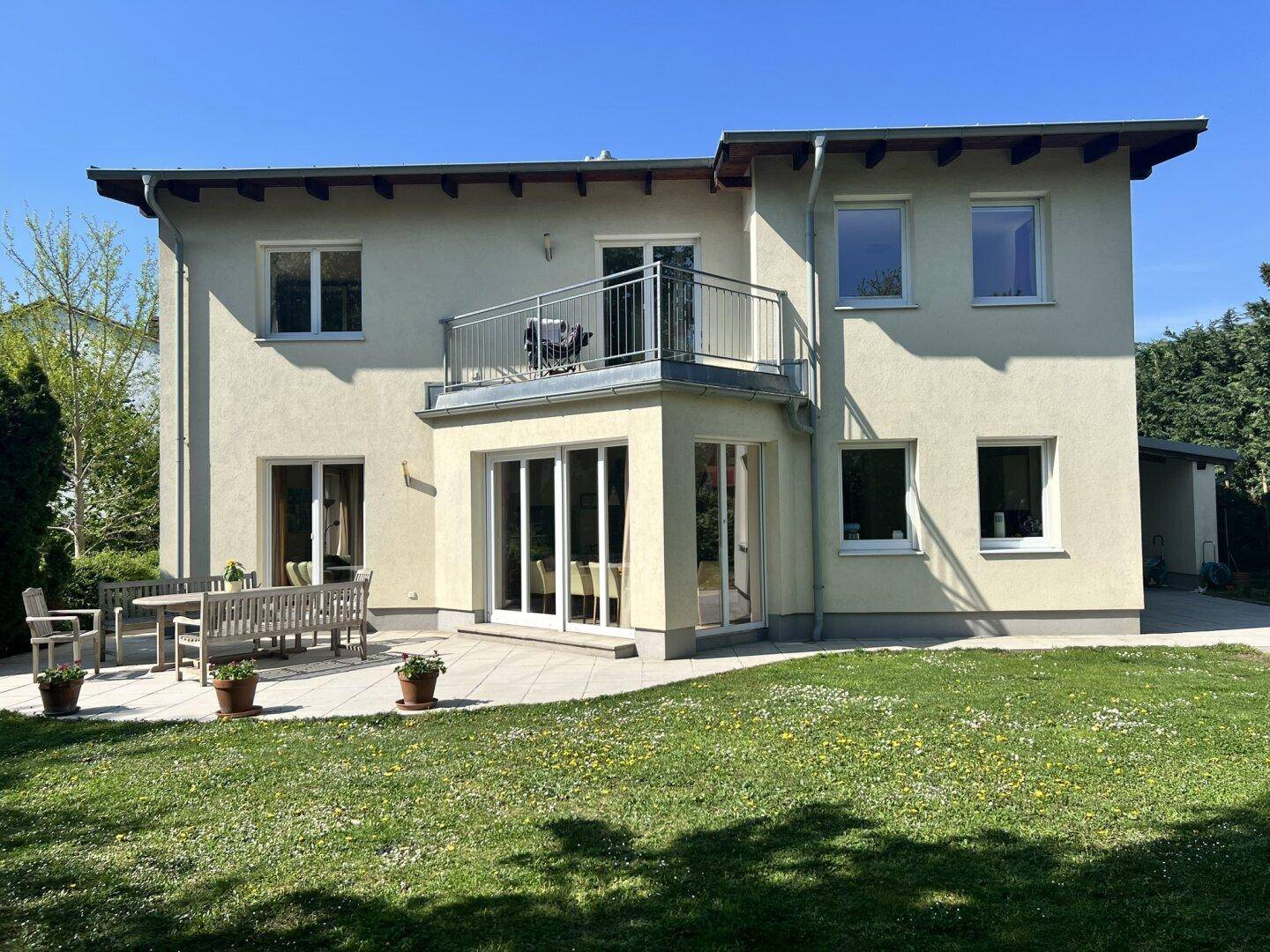 Rückseite des Hauses mit großer Terrasse, Balkon und weitläufigem Gartenbereich.