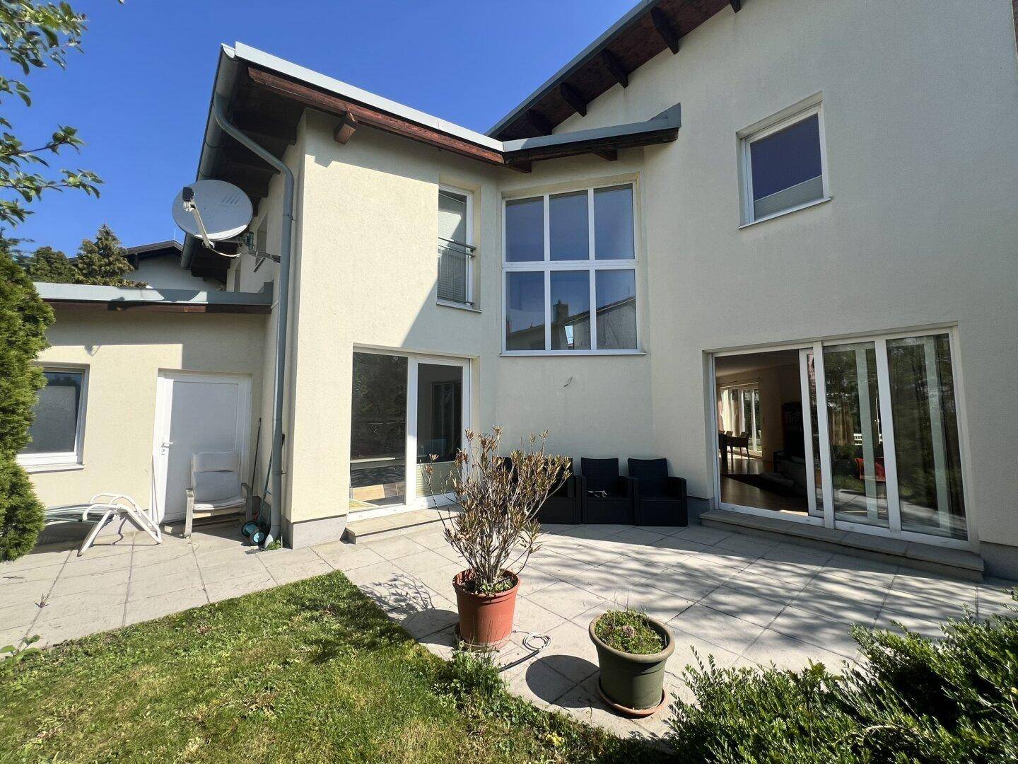 Große Terrasse an der Rückseite des Hauses mit Sitzgelegenheiten und Gartenblick.