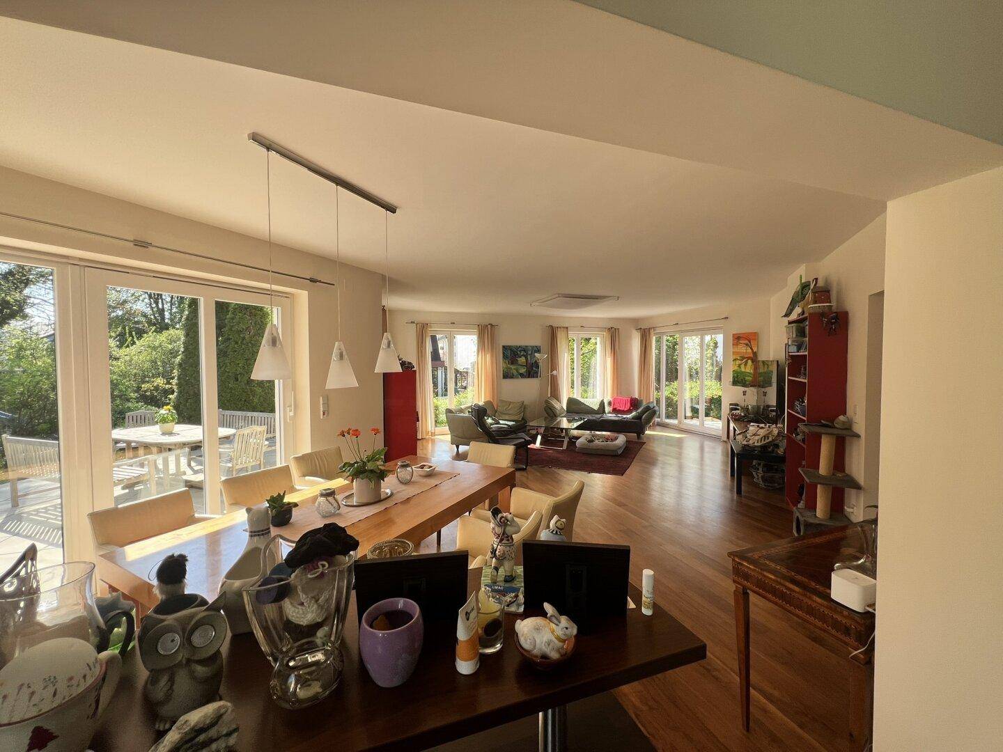Weitläufiger Wohn-Essbereich mit Holzboden, Esstisch und Blick in den Garten.
