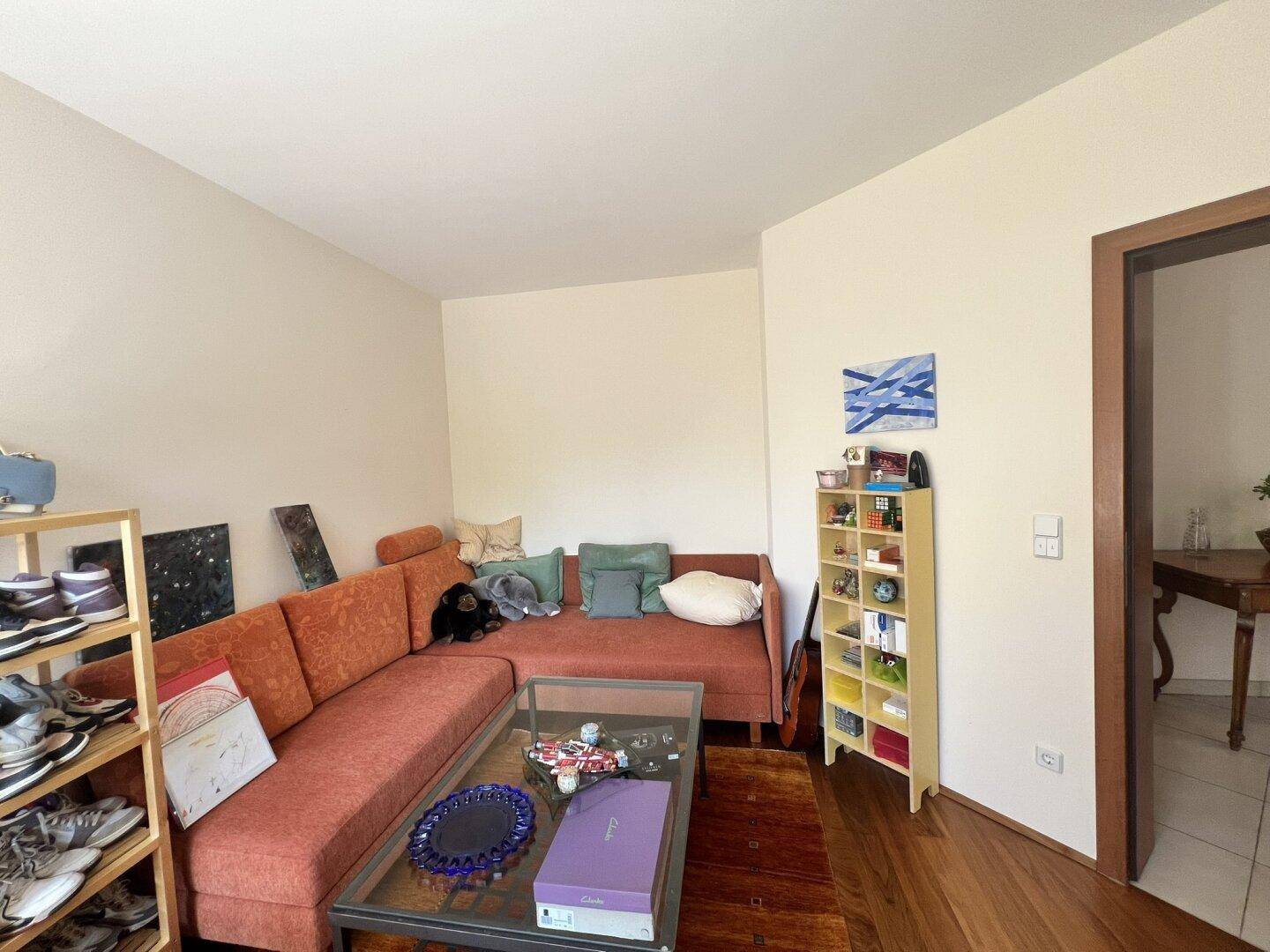 Gemütlicher Wohnbereich mit Ecksofa, Holzboden und Blick auf den Garten.