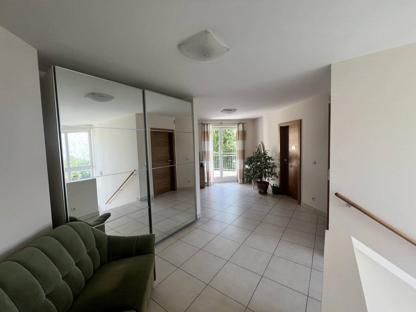 Heller Flur im Obergeschoss mit Fliesenboden, Spiegelschrank und Zugang zum Balkon.