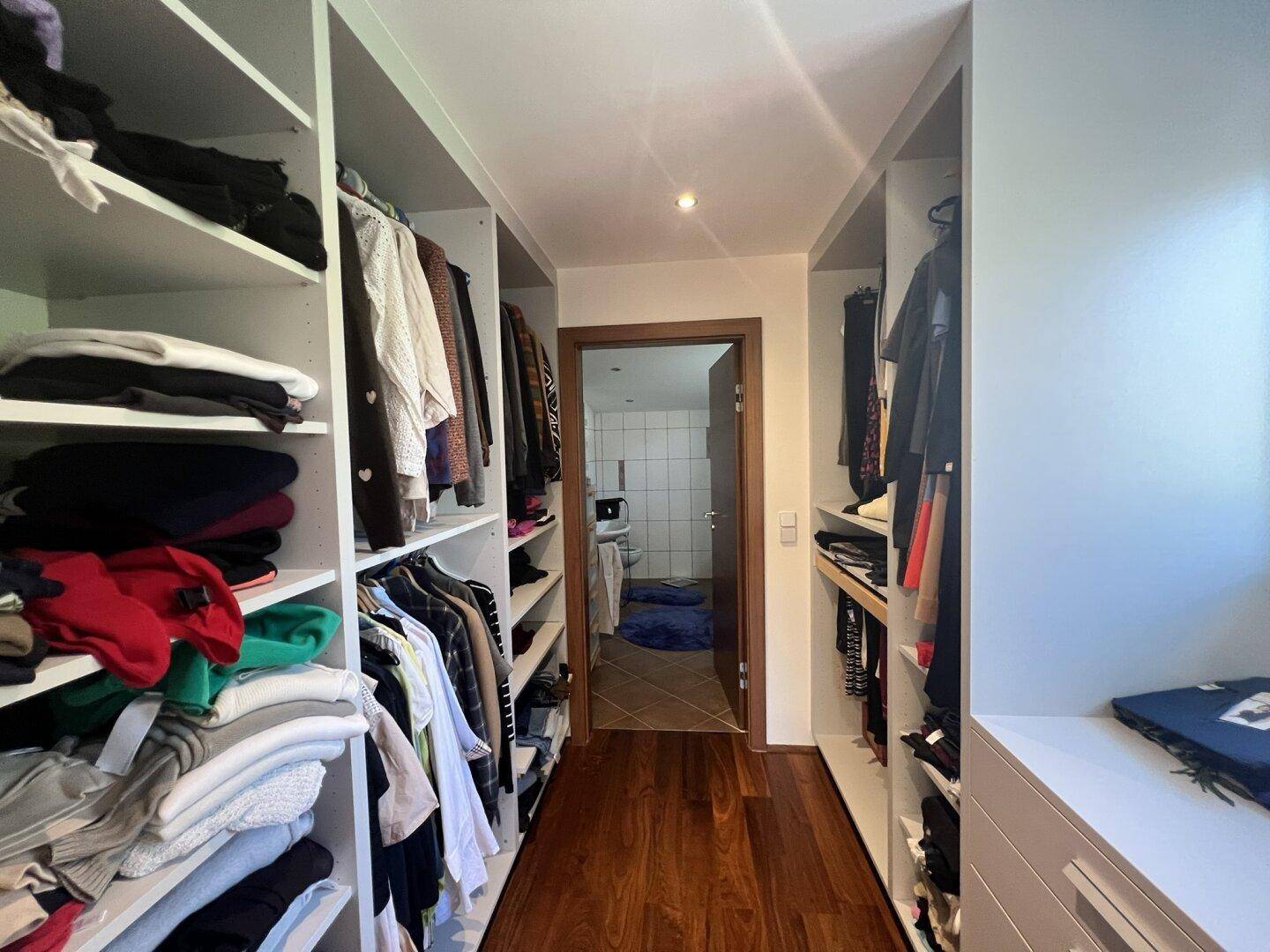 Begehbarer Kleiderschrank mit viel Stauraum und Holzboden.