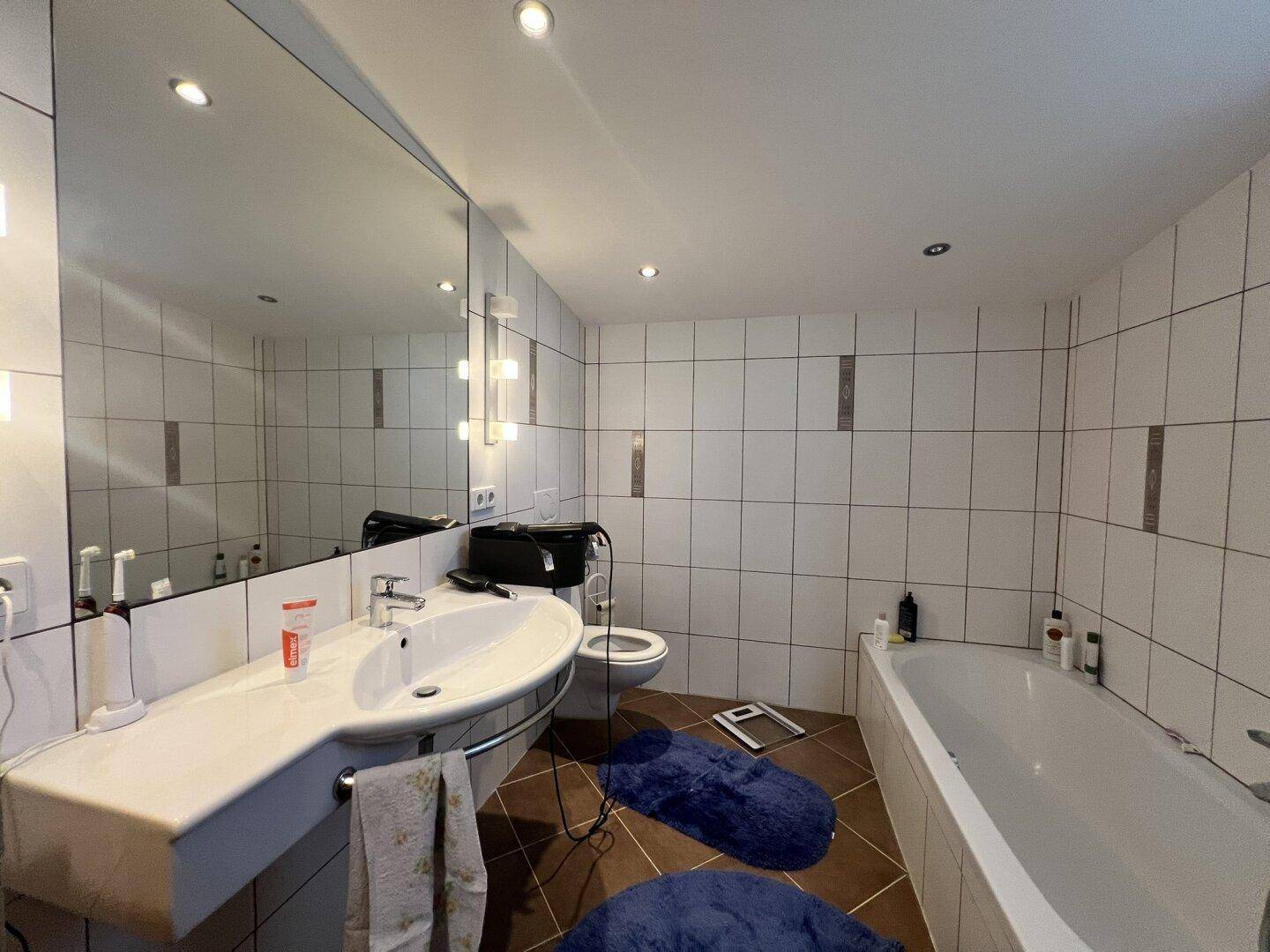 Modernes Badezimmer mit Badewanne, Waschbecken und großen Spiegeln.