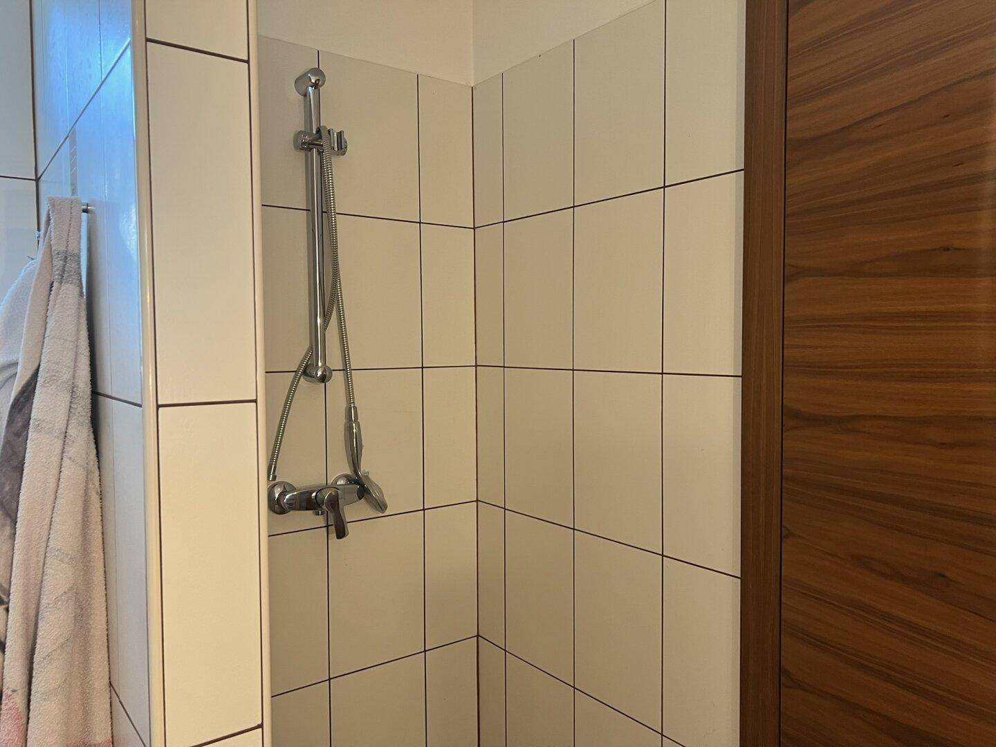 Duschbereich im Badezimmer mit weißen Fliesen und moderner Armatur.