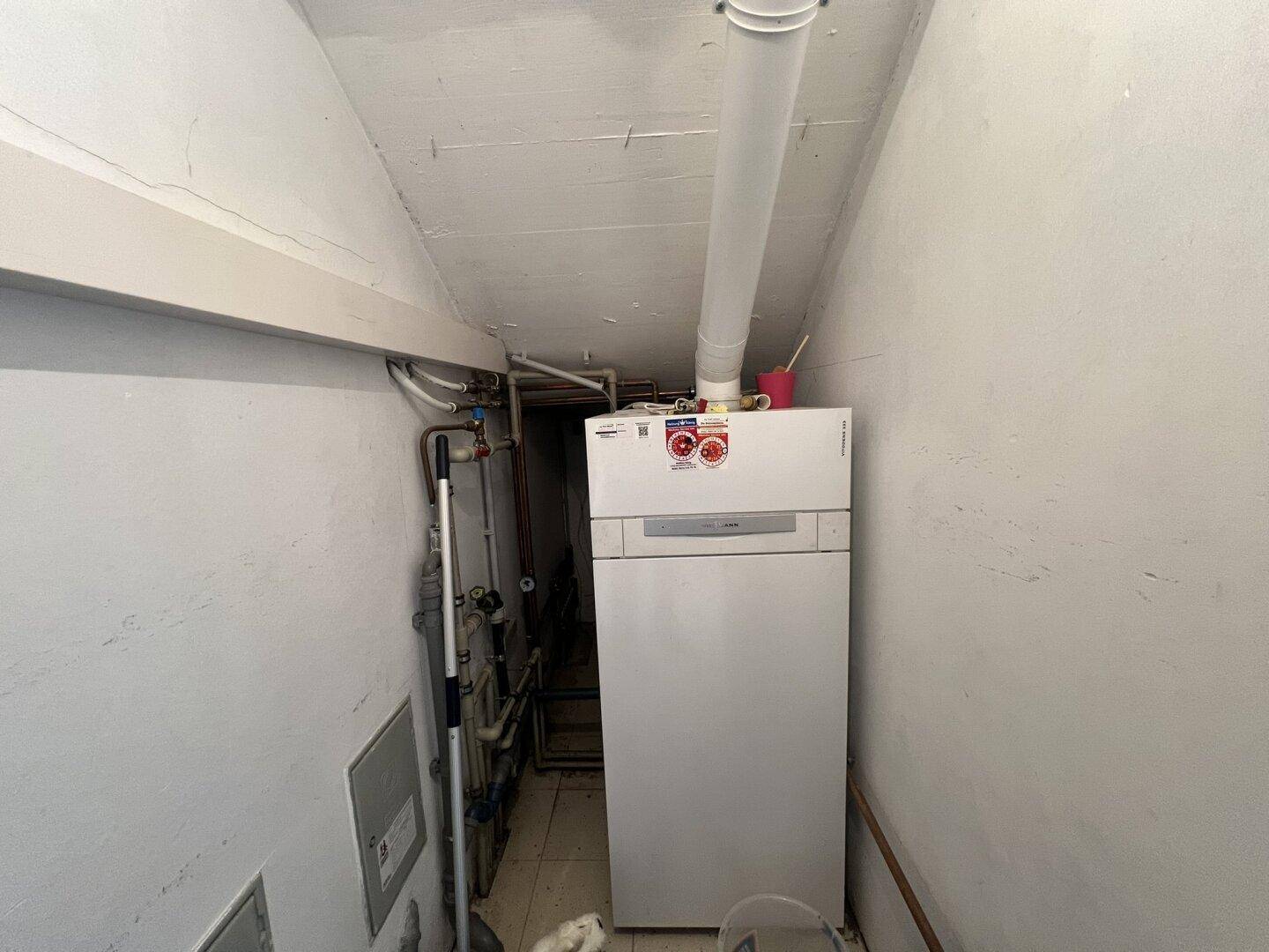 Heizungsraum mit Warmwasserbereiter und sichtbaren Rohrleitungen.