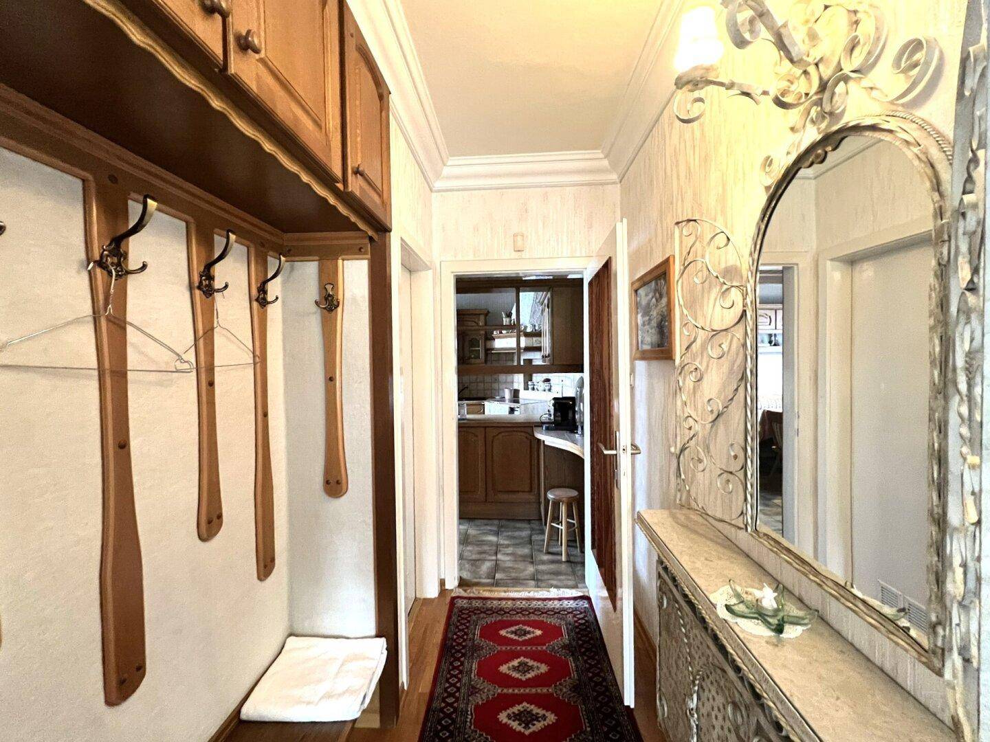 Heller Flur mit Garderobe, dekorativem Spiegel und Blick in die angrenzende Küche.