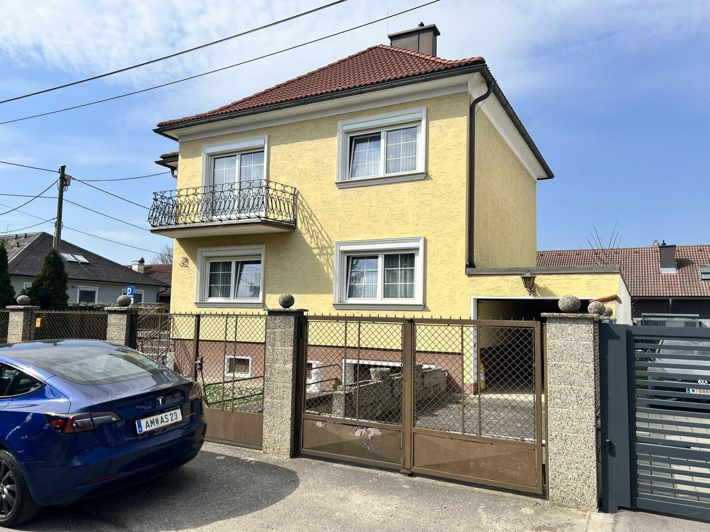 Seitenansicht des gelben Hauses mit Einfahrt und einem blauen Auto davor.