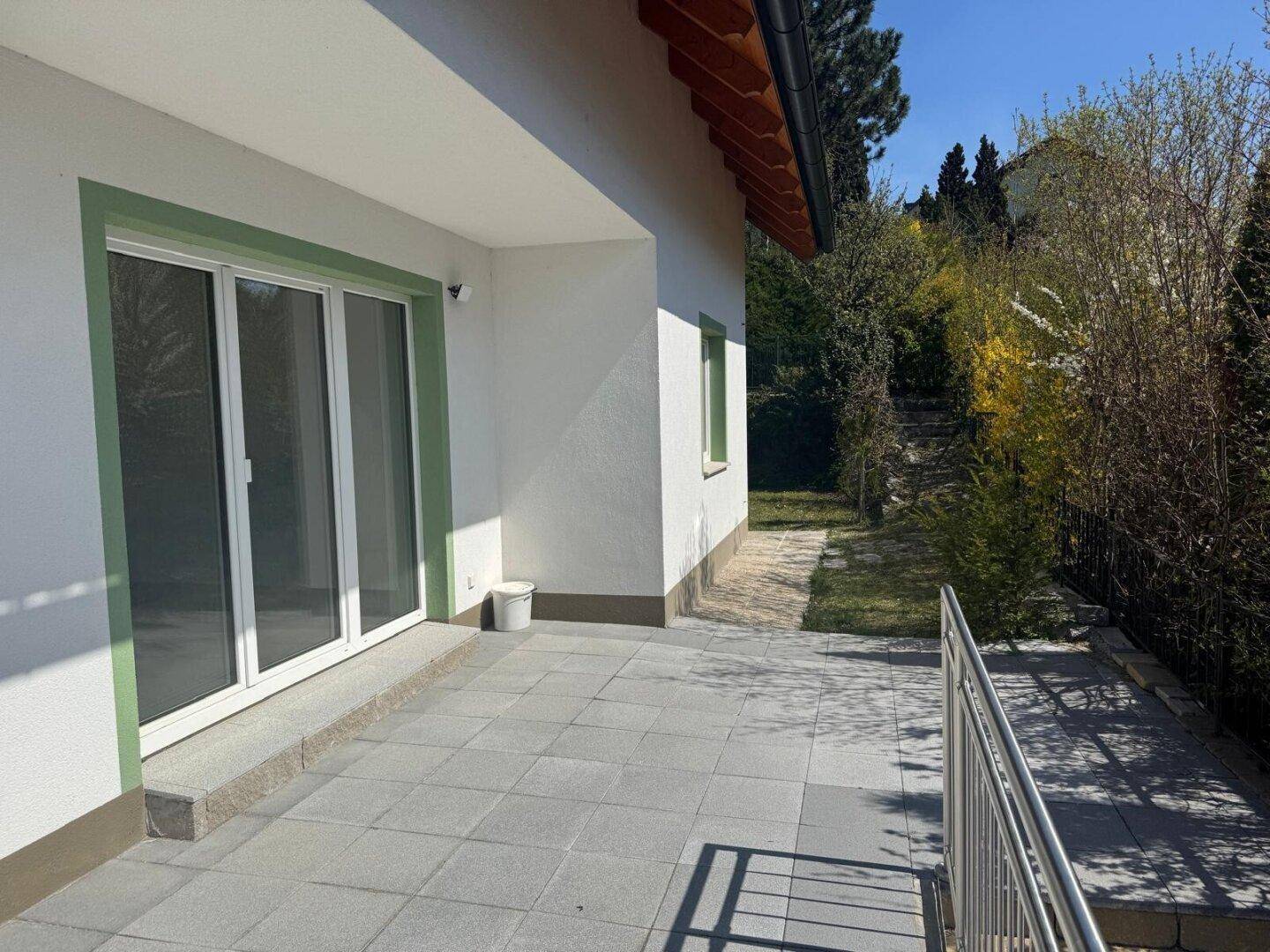 Geräumige, gepflasterte Terrasse mit großen Schiebetüren, die viel Licht ins Innere lassen.