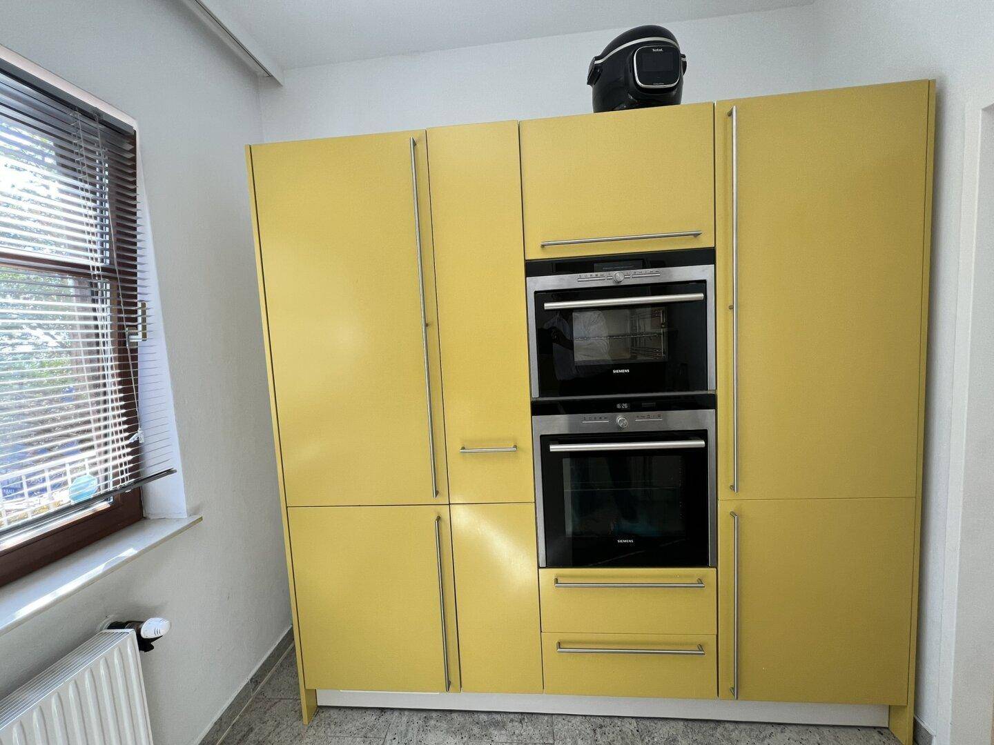 Gelbe Küchenschränke mit integriertem Backofen und Mikrowelle von Siemens.