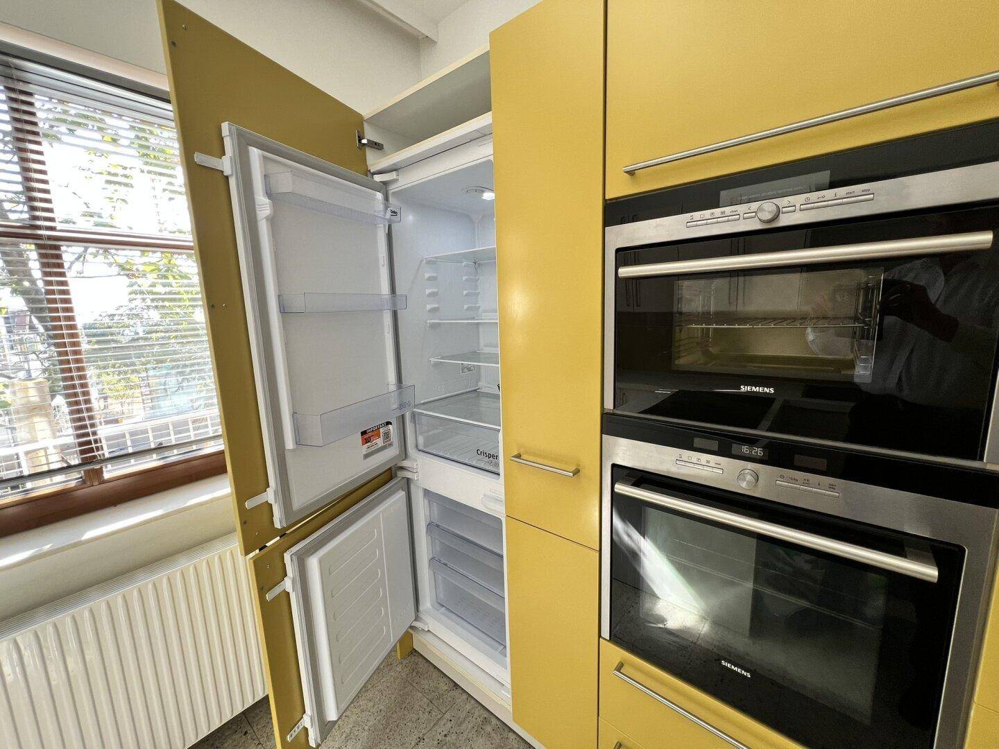 Offener Kühlschrank und Gefrierschrank neben den gelben Küchenschränken mit Siemens-Geräten.