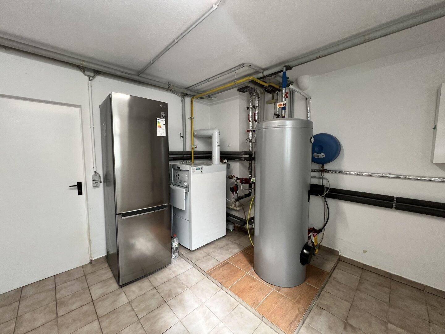 Hauswirtschaftsraum mit Warmwasserspeicher, Heizkessel und einem großen Kühlschrank.