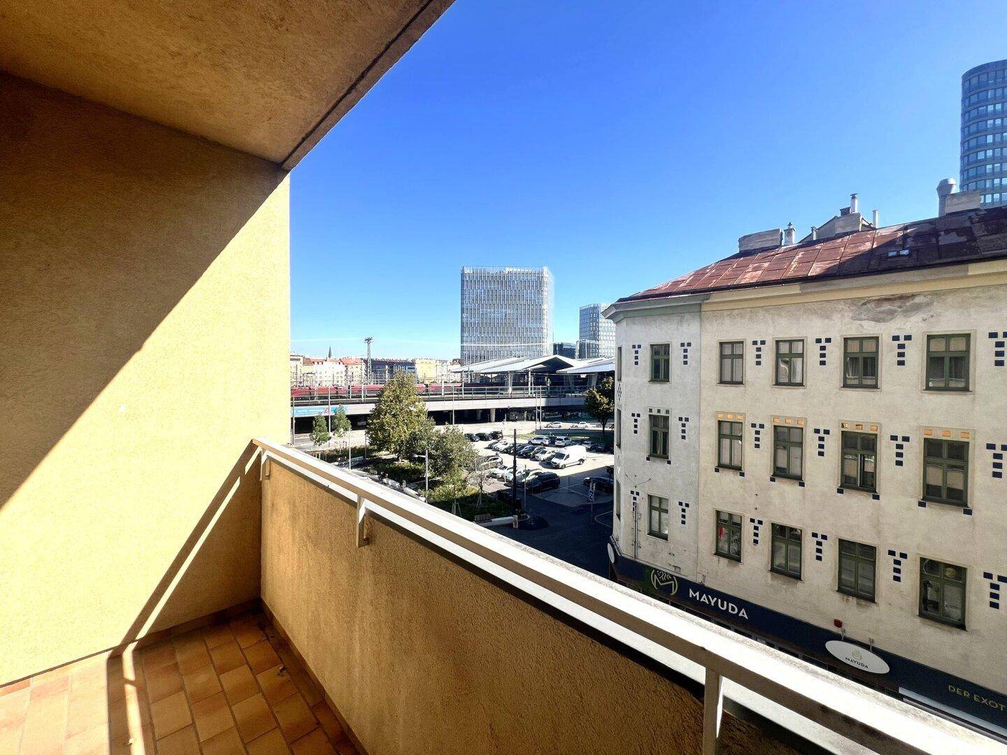 Balkon mit Fliesenboden und Blick auf die Stadt und umliegende Gebäude.