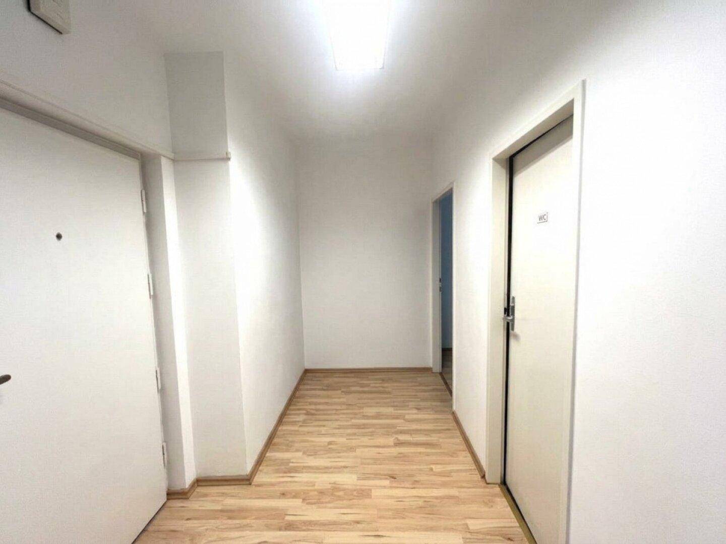 Langer, heller Flur mit Laminatboden und Zugang zu verschiedenen Räumen.