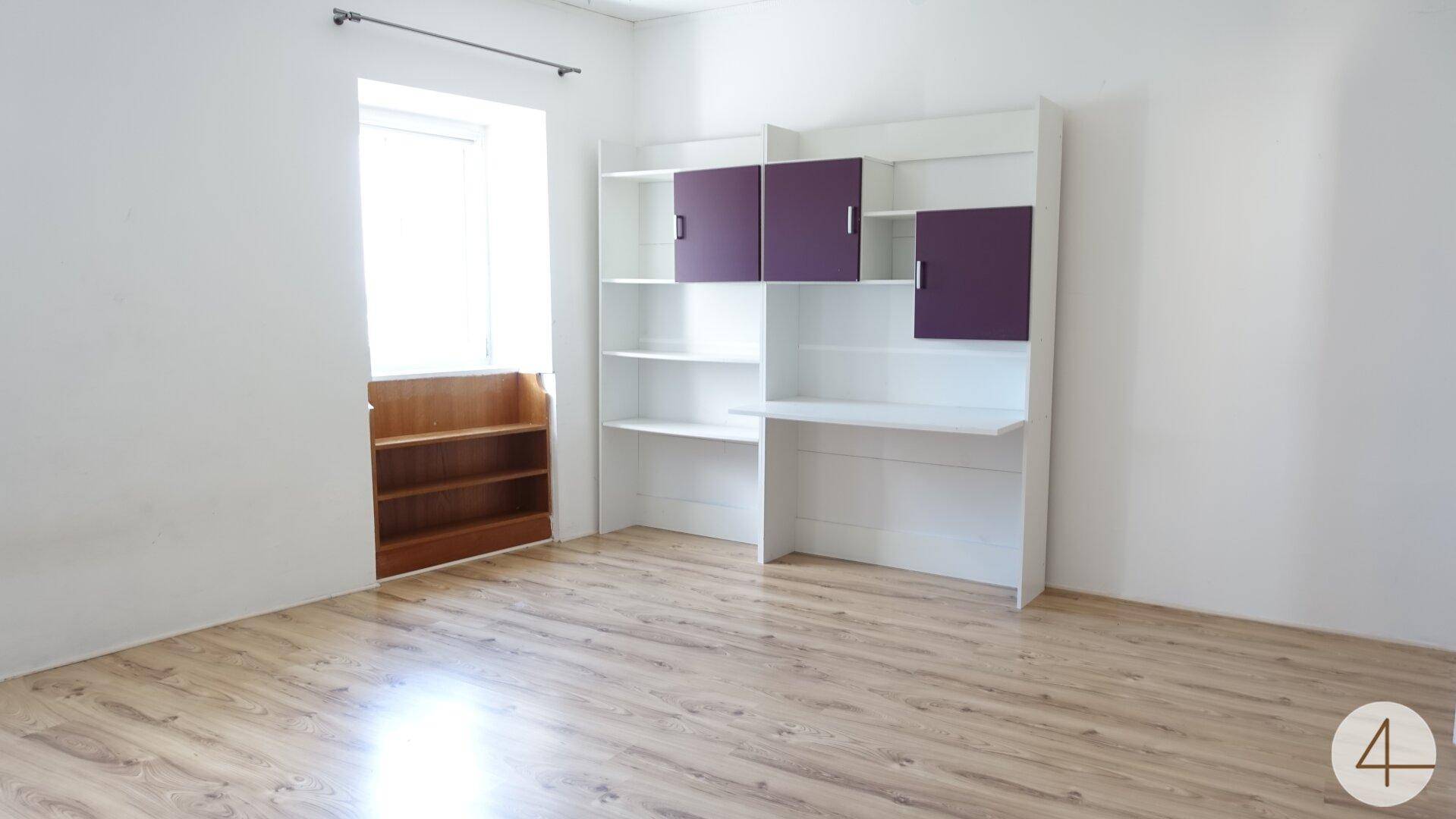 Heller Raum mit Laminatboden, weißen Wänden und einem Regal mit lila Akzenten.