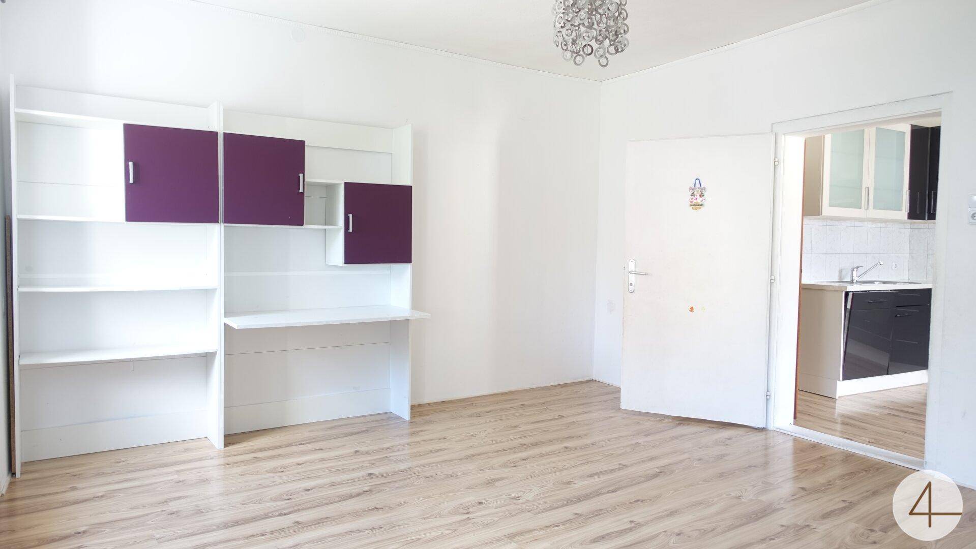 Geräumiger Raum mit Laminatboden und offenem Zugang zur modernen Küche.