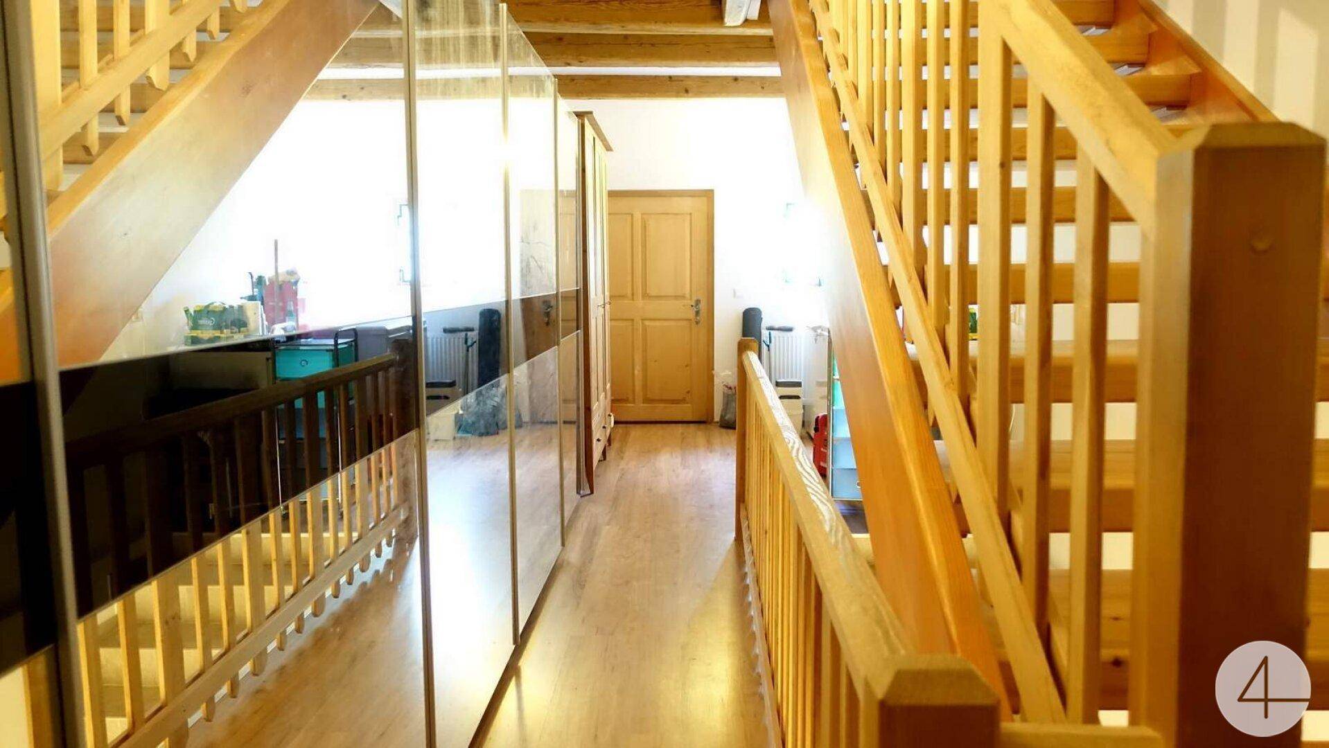 Heller Flur mit Holztreppe, Spiegelschränken und Holzboden.