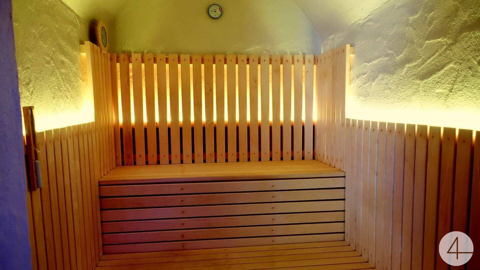 Innenansicht einer modernen Holzsauna mit Sitzbänken und indirekter Beleuchtung.