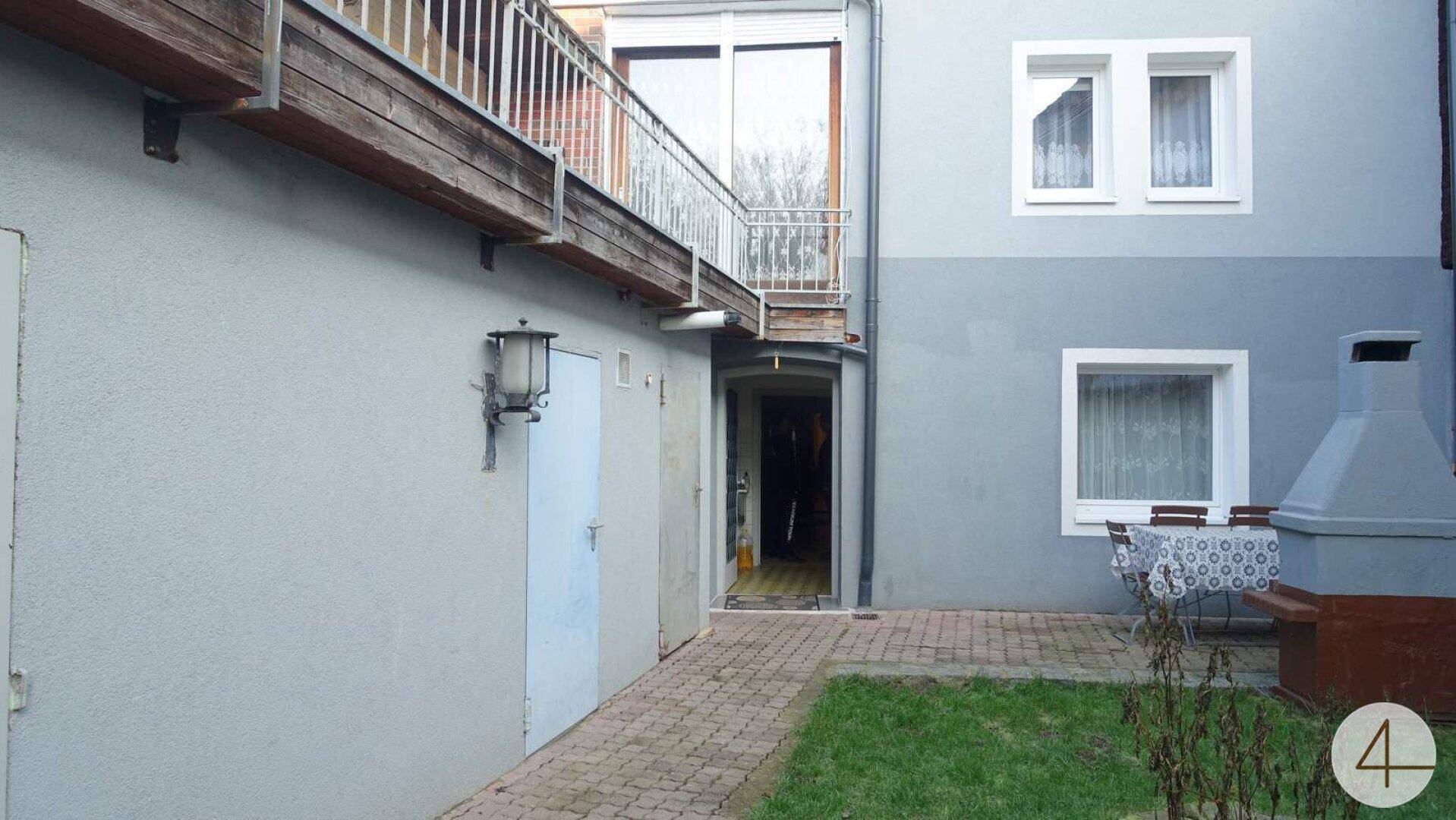Kleiner Gartenbereich mit Grillplatz und Zugang zu einem Balkon im Obergeschoss.