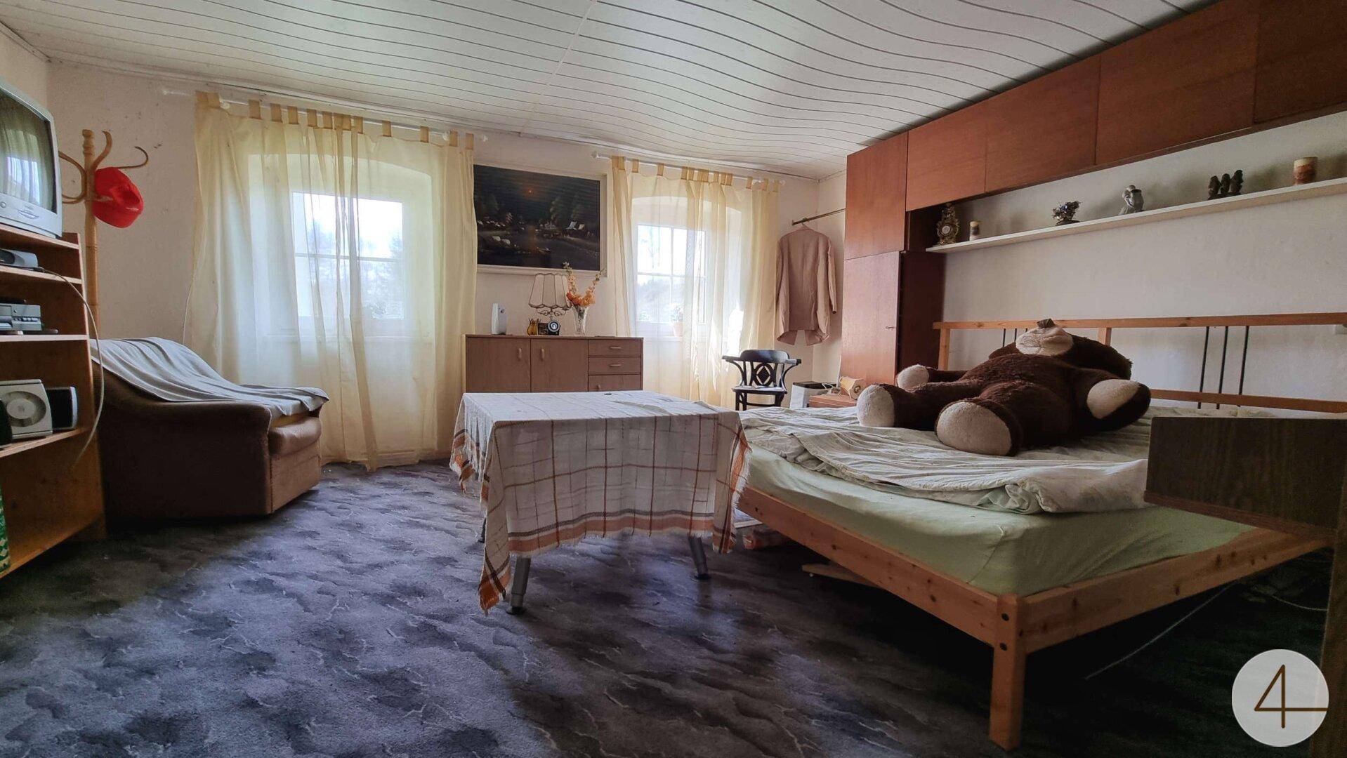 Schlafzimmer mit Holzbett, Teppichboden und einem großen Schrank an der Wand.