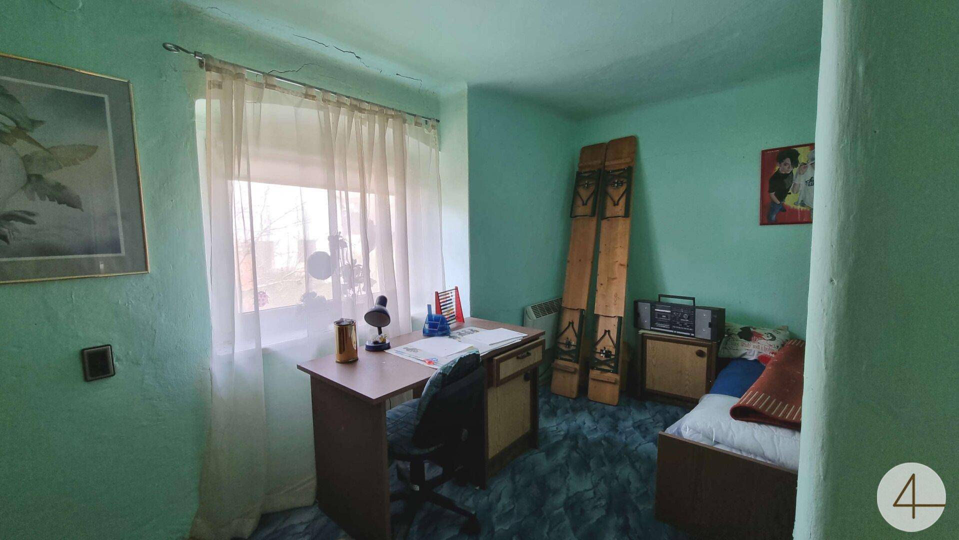 Kleines Arbeitszimmer mit hellgrünen Wänden, Schreibtisch und einem Fenster für Tageslicht.