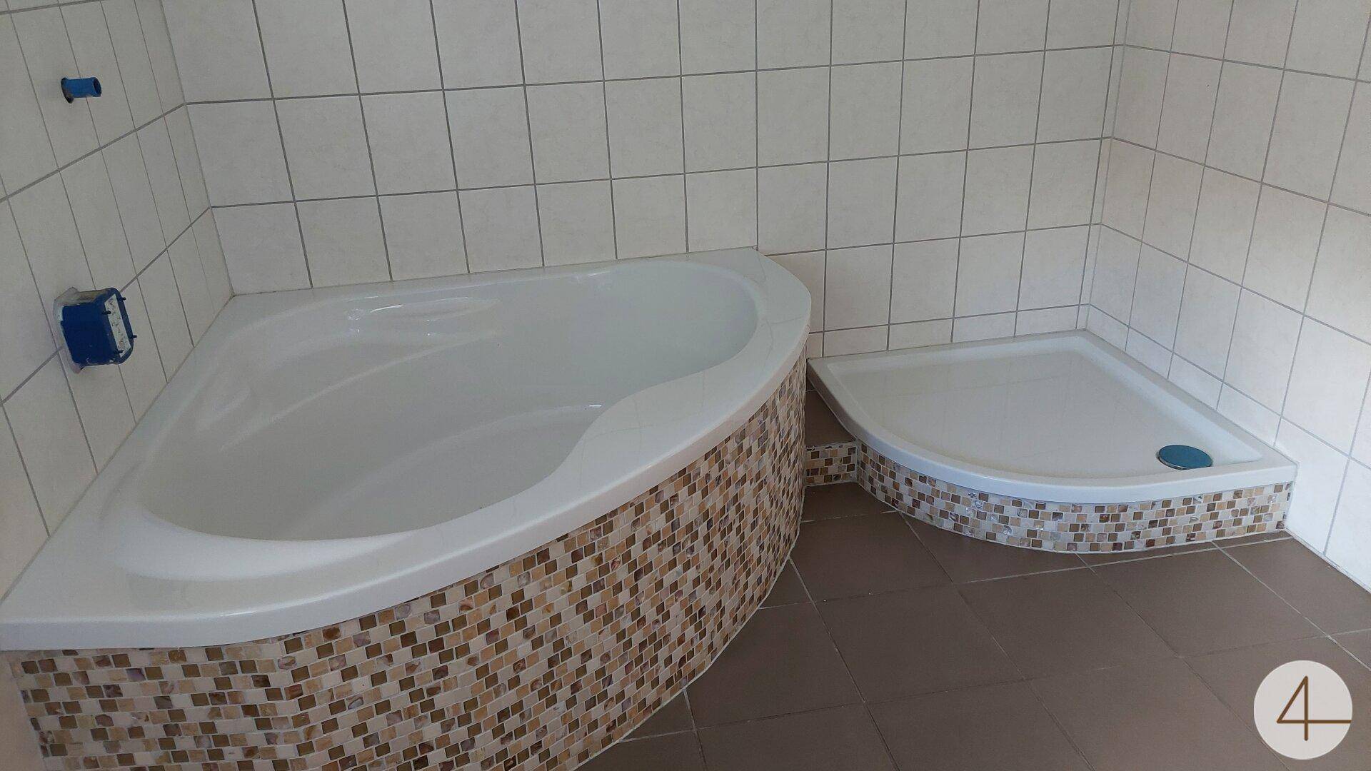 Badezimmer mit Eckbadewanne und Duschwanne, verziert mit Mosaikfliesen.
