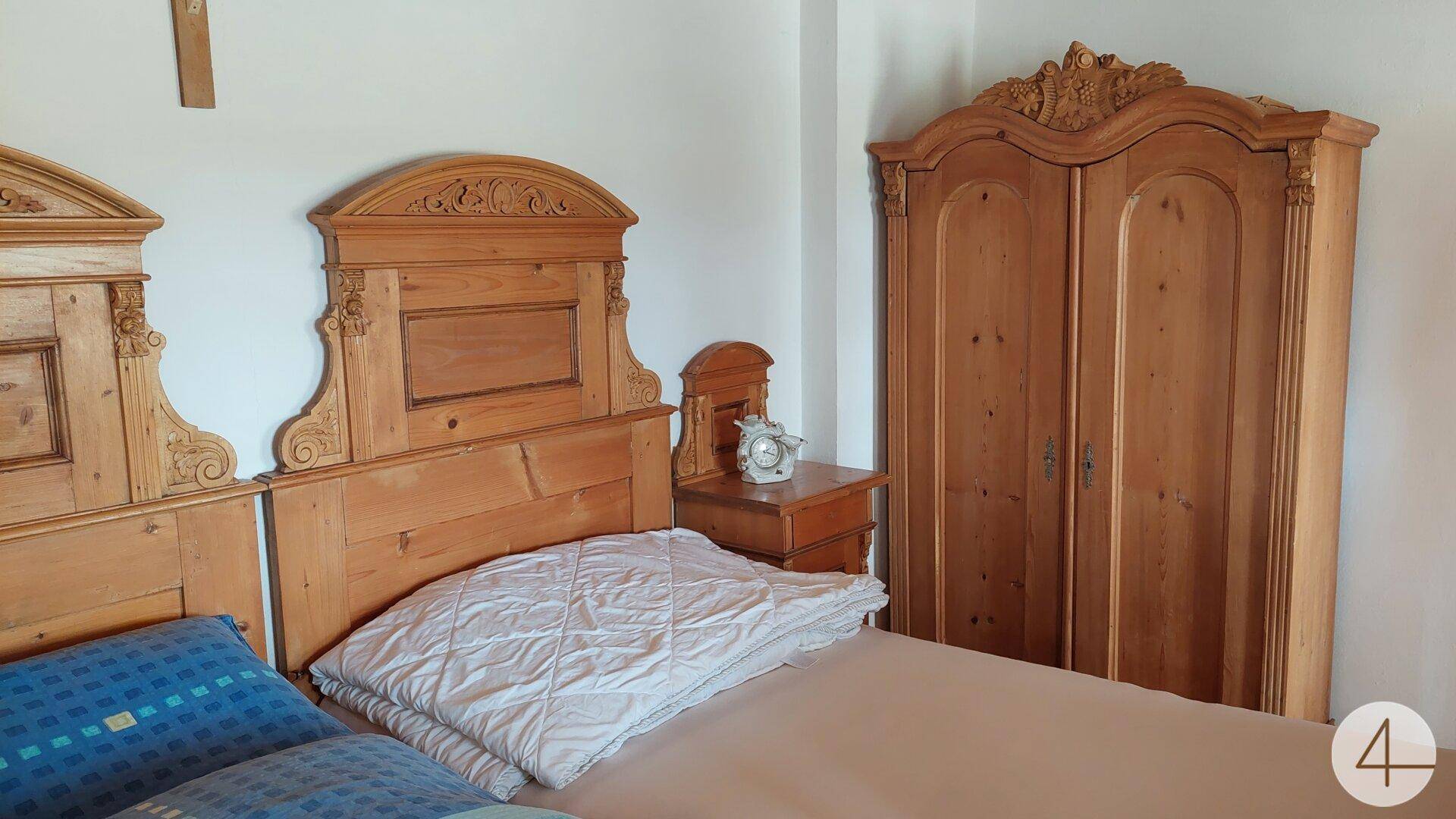 Schlafzimmer mit traditionellen Holzbetten und einem passenden Kleiderschrank im Landhausstil.