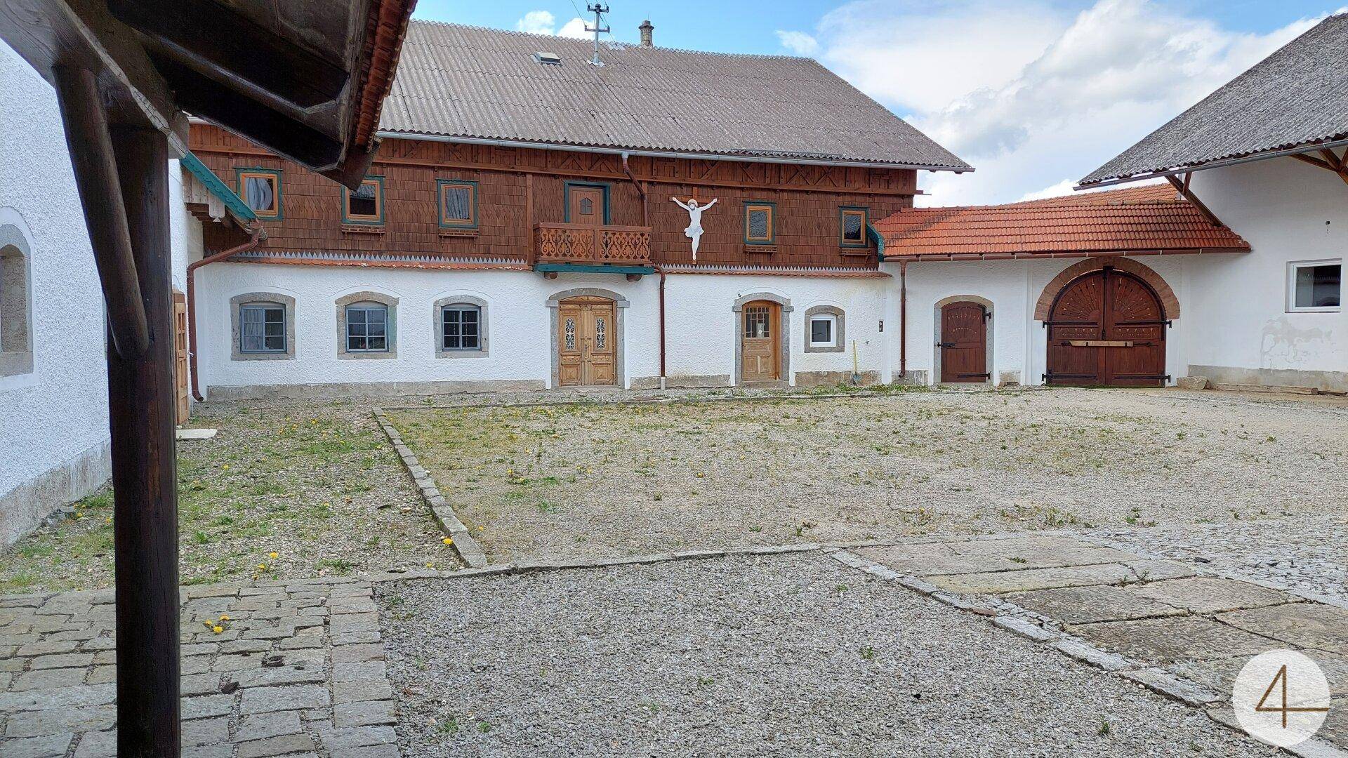 Geräumiger Kieshof zwischen traditionellen Gebäuden mit Holzelementen und weißer Fassade.