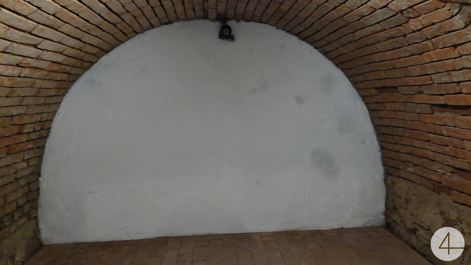 Historischer Gewölberaum mit Ziegelbögen und weiß verputzter Wand, rustikaler Charme.