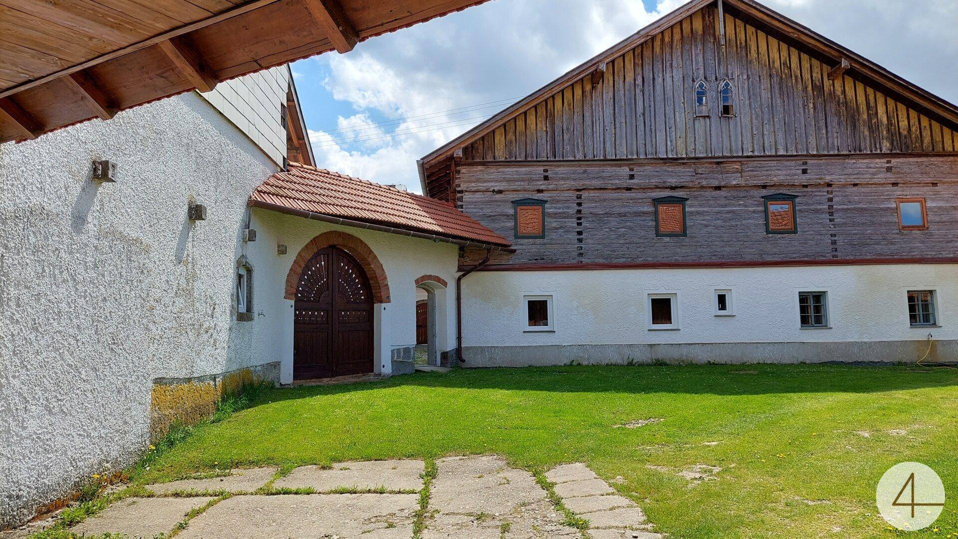 Grüner Innenhof zwischen traditionellen Gebäuden mit Holzelementen und weißer Fassade.