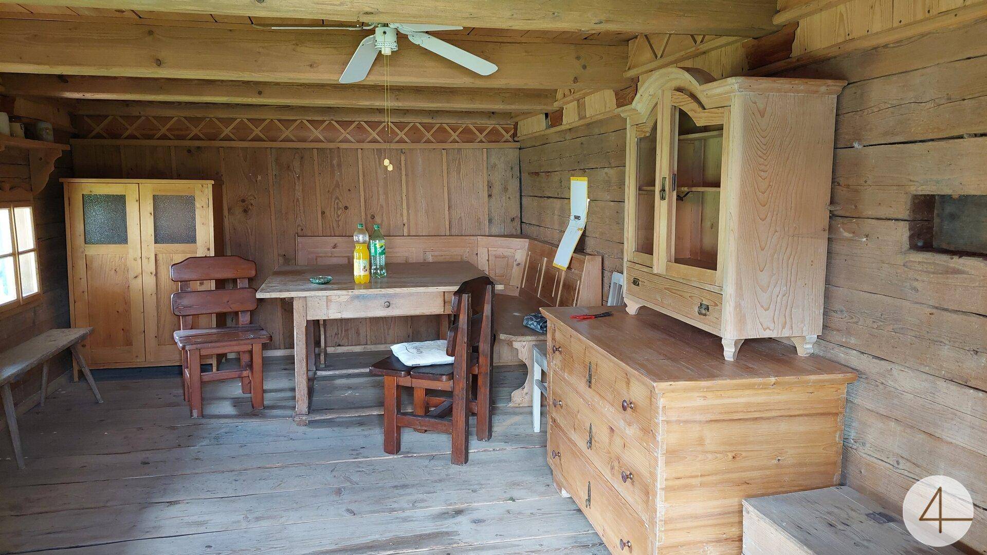Rustikaler Wohnraum mit Holzverkleidung, Holztisch und Schränken, traditionell eingerichtet.